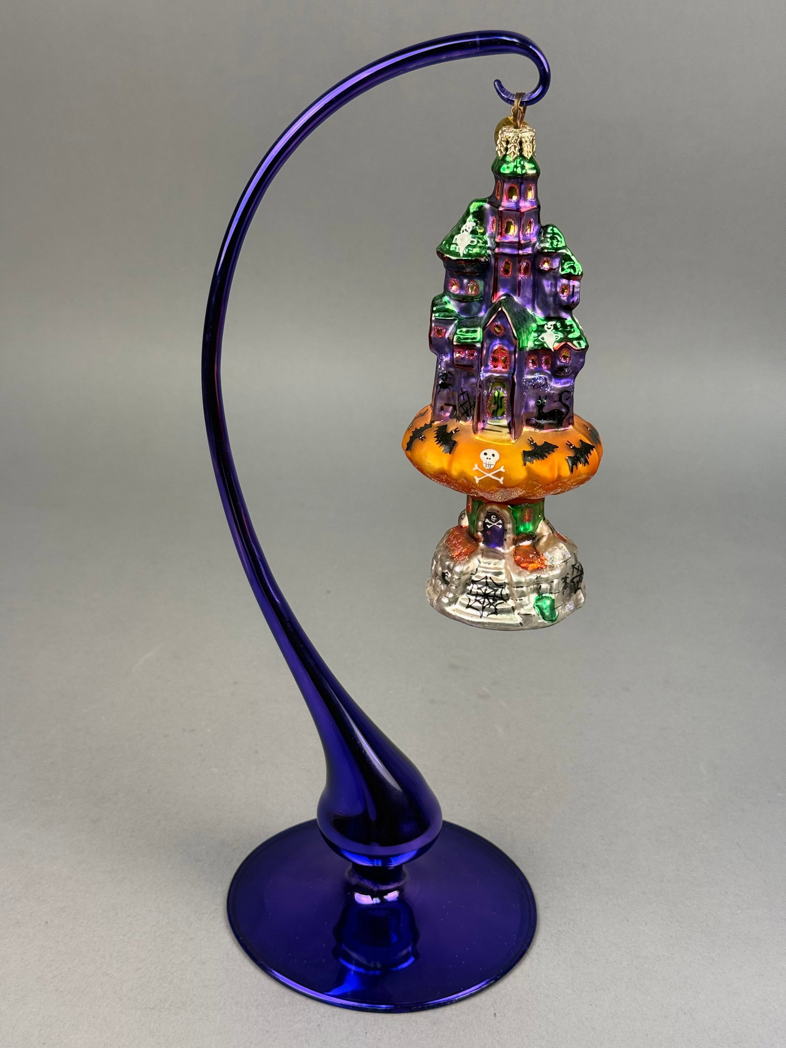 Radko Halloween Totem Hand Blown Glass Ornament: A hand-blown glass Halloween-themed ornament produced by Christopher Radko. The ornament includes a gold-toned crown-style hanging cap with the signature Christopher Radko eight-pointed star metal cha