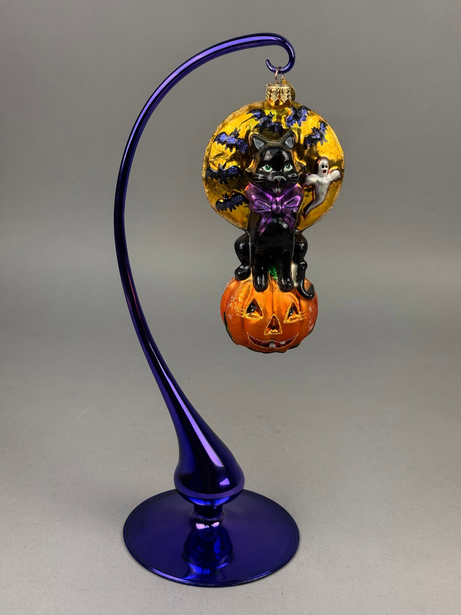 Radko Glass Halloween Ornament with Black Cat and Jack-o-Lantern: This large, multi-element holiday ornament is crafted from mold-blown glass and hand-painted with glazes and glitter accents from Christopher Radko. The ornament is finished with a gold-toned metal cr