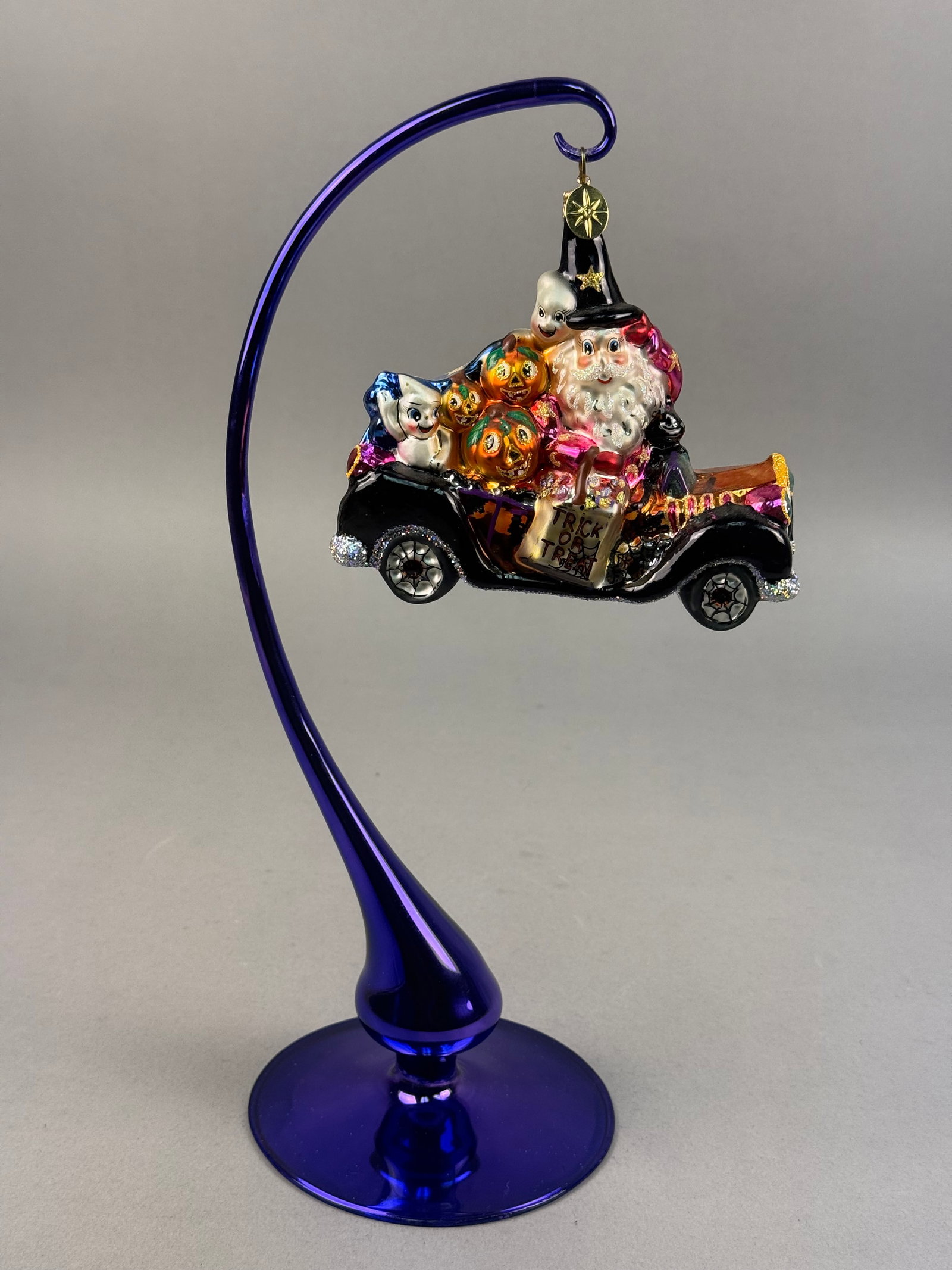 Radko Scream Team Halloween Glass Ornament: Ornament stand NOT INCLUDED. A hand-blown glass ornament titled Scream Team produced by Christopher Radko. A gold-toned metal charm featuring the maker's signature eight-pointed starburst motif is att