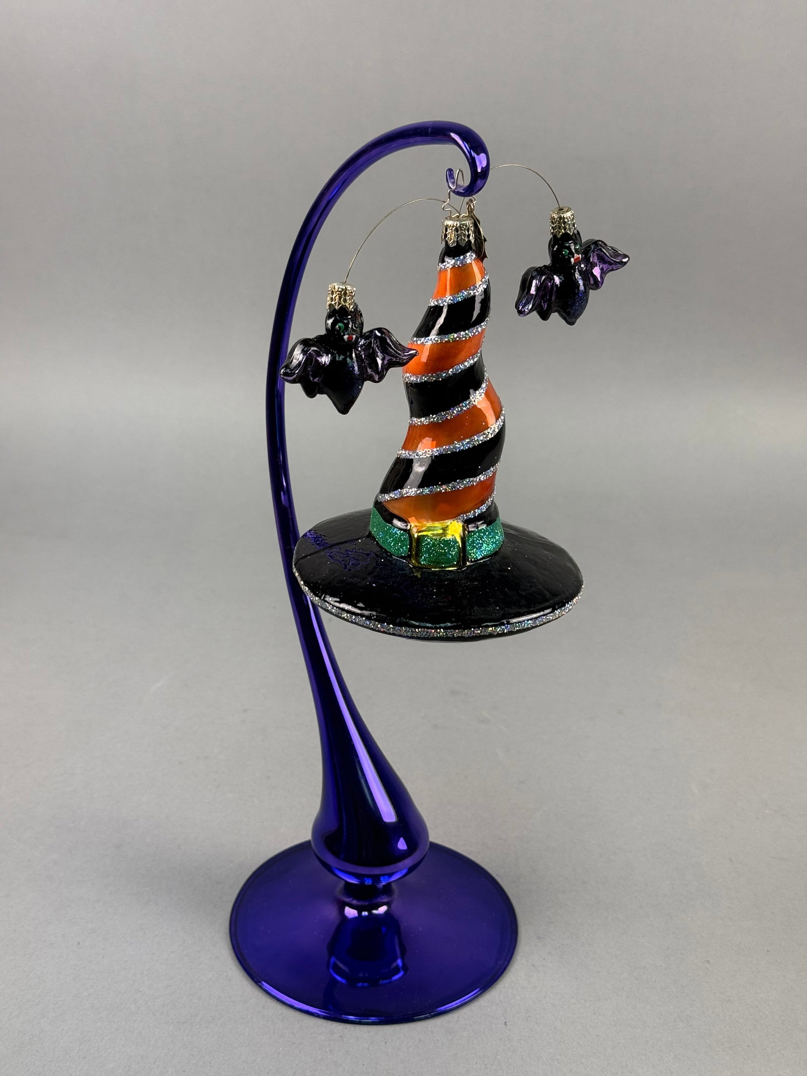 Radko Halloween Glass Ornament with Suspended Bats: Christopher Radko, possibly the Grave Tidings pattern, this hand-blown glass Halloween ornament depicts a whimsical witch's hat with suspended bat accents. The ornament is fitted with a gold-tone meta