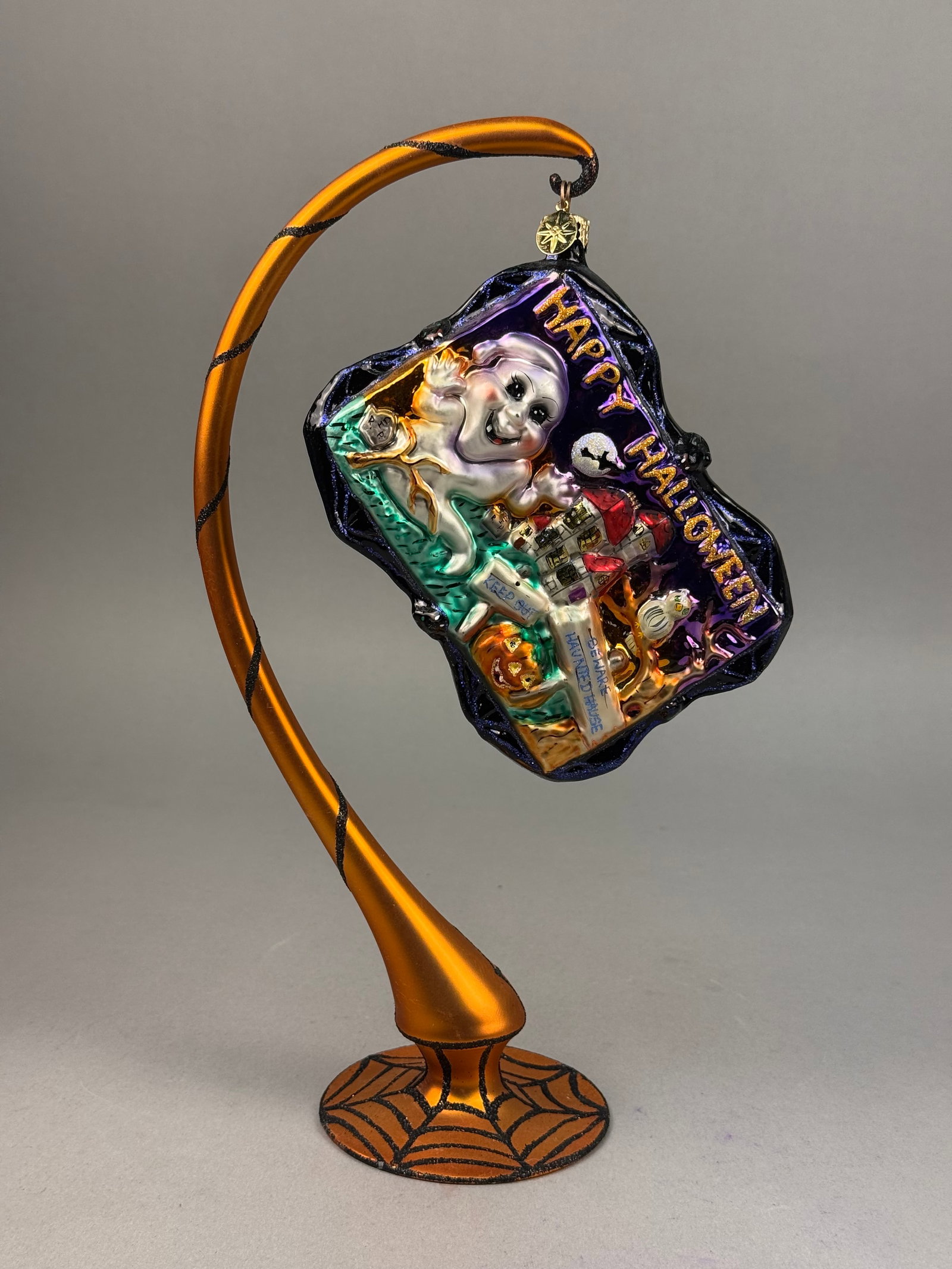 Radko Happy Halloween Postcard Glass Ornament: A mouth-blown glass holiday ornament by Christopher Radko, designed in the form of a vintage-style postcard. It retains the signature gold-tone metal charm with an embossed five-pointed star. Ornament