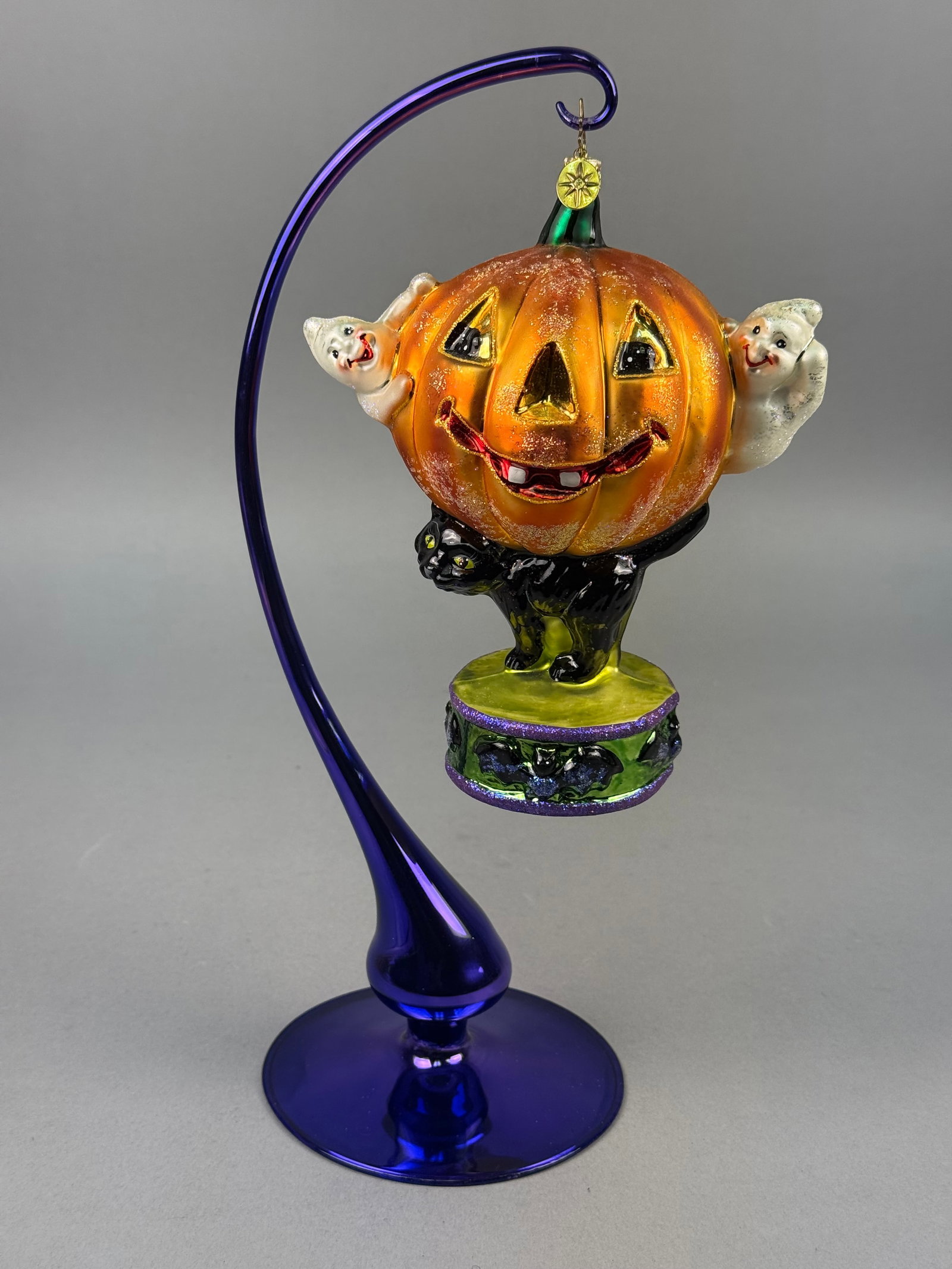 Radko Blown Glass Jack-O-Lantern Halloween Ornament: This hand-blown glass ornament is a collectible holiday piece by Christopher Radko. The surface is detailed with hand-applied multicolored fine glitter highlights. A gold-tone metal cap is fitted at t