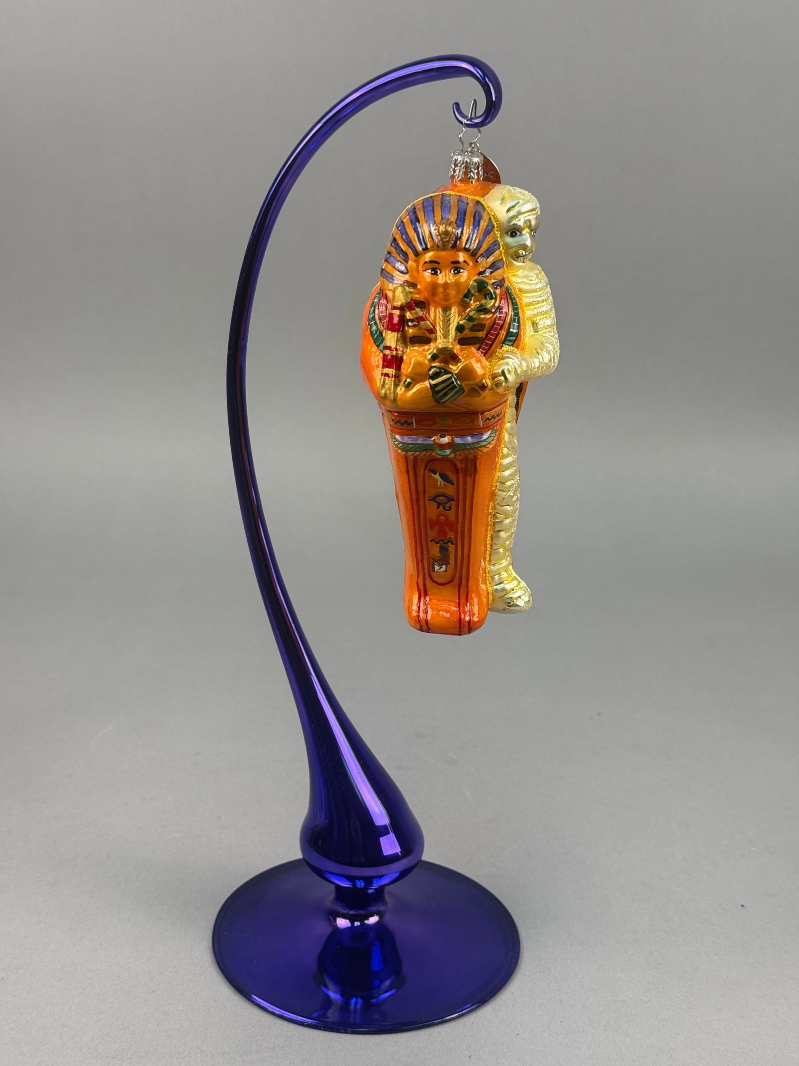 Radko Blown Glass Egyptian Sarcophagus Ornament: This mouth-blown glass Christmas ornament is produced by Christopher Radko and is designed in the form of an ancient Egyptian sarcophagus. The ornament includes a silver-toned metal cap and hanging lo