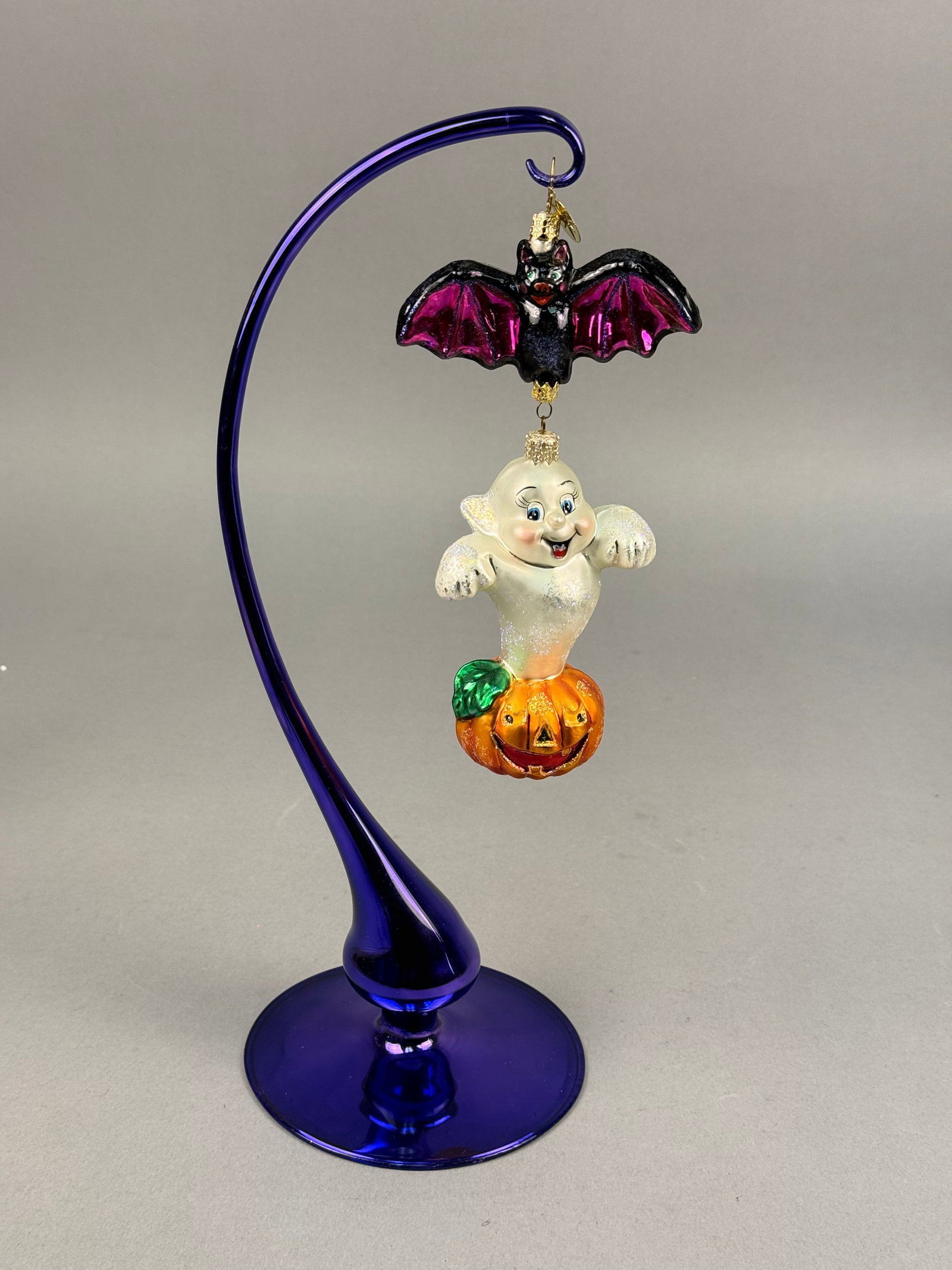Radko Boo Buds Halloween Glass Ornament: Christopher Radko Boo Buds Halloween themed two-part hand-blown glass ornament with a cobalt blue glass stand. The set includes a bat ornament featuring a black glittered body and iridescent magenta w