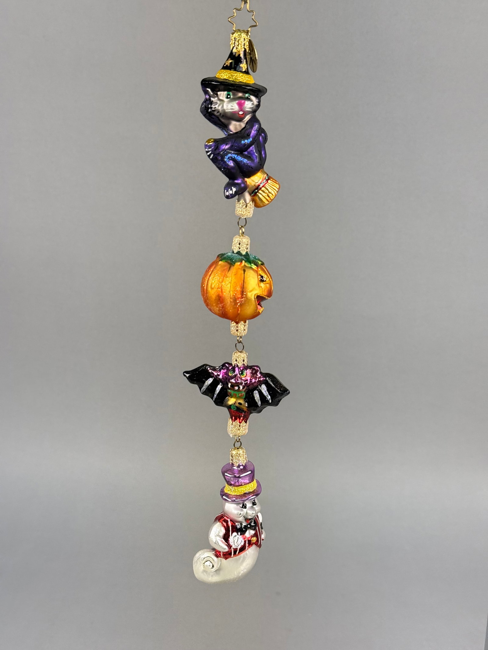 Radko Halloween Blown Glass Ornament: The pieces are finished with hand painted details and glitter highlights throughout. Attached to the hanging loop is a circular gold tone metal tag featuring the trademark Christopher Radko signature 