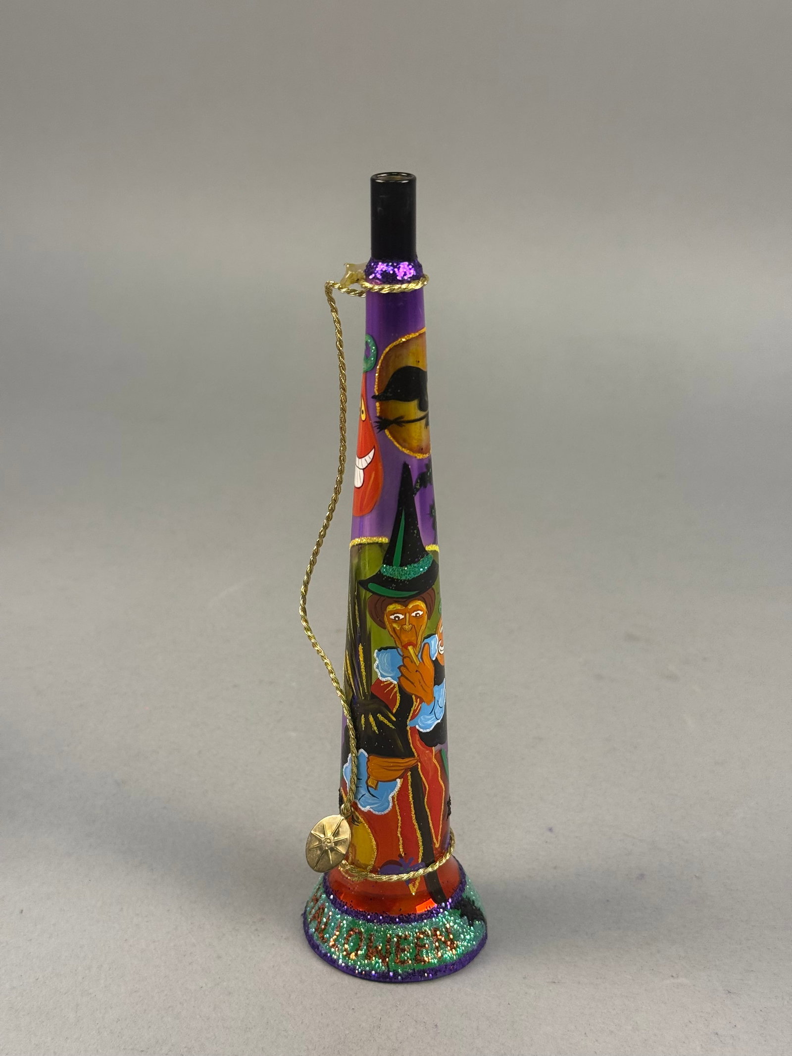 Hand-Blown Painted Glass Halloween Decorative Party Horn: This is a hand-blown glass holiday decorative item fashioned in the shape of a trumpet or party horn. The piece is constructed from translucent purple mouth-blown glass and features a continuous hand-
