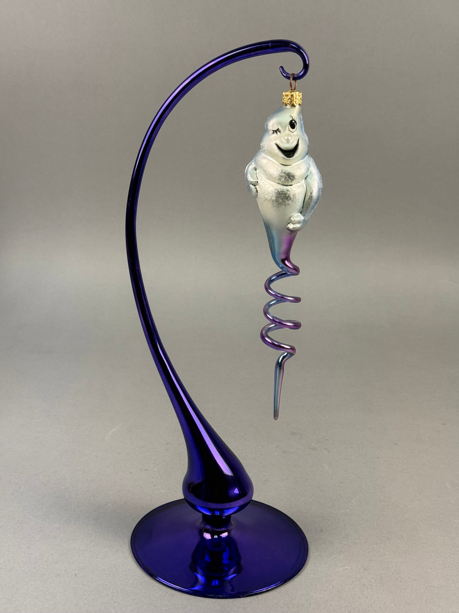 Radko Blown Glass Ghost Spiral Ornament: Ornament stand NOT INCLUDED. A hand-blown glass ornament manufactured by Christopher Radko. The ornament is shaped as a stylized ghost with a frosted white iridescent body and black hand-painted facia