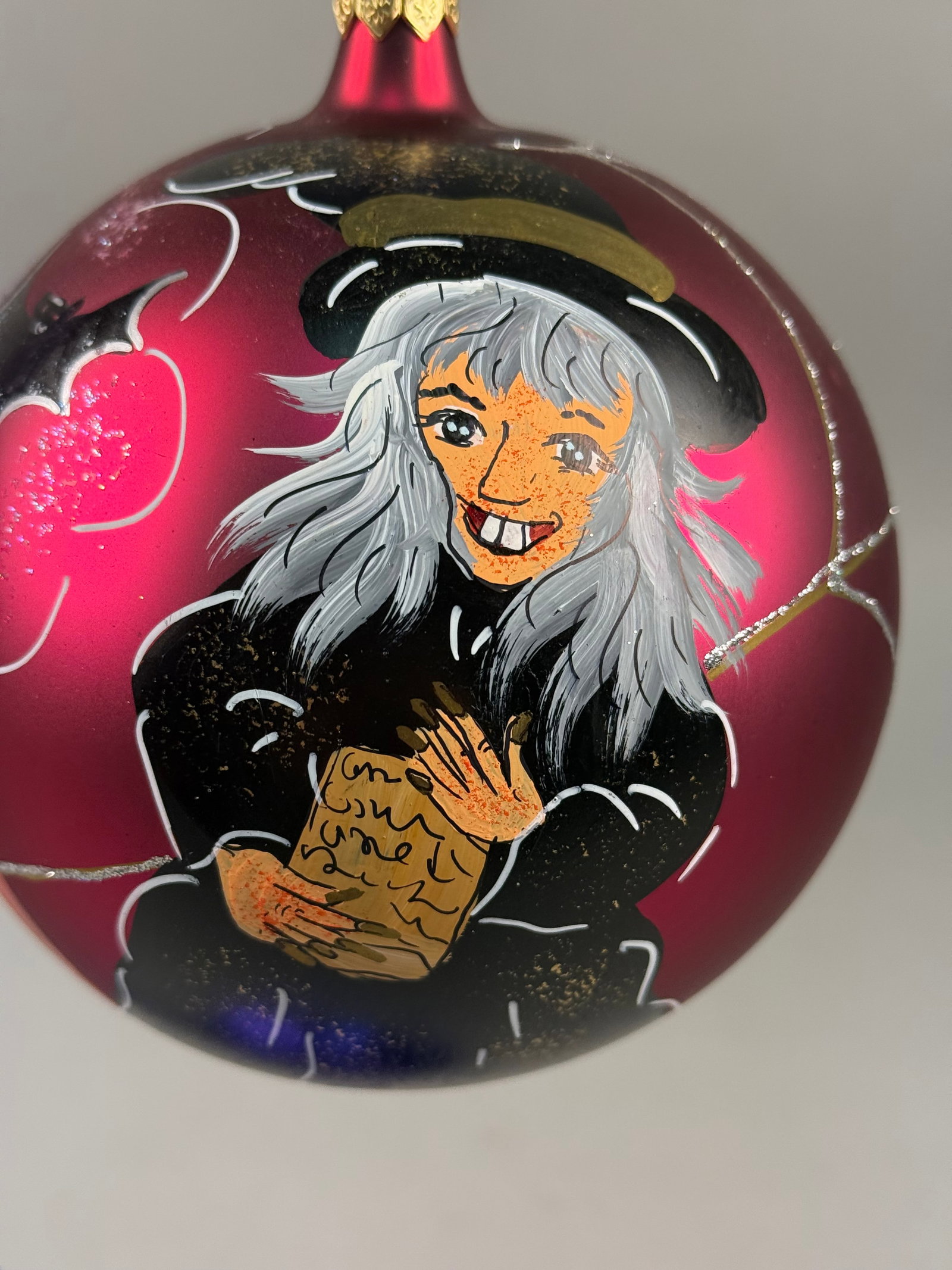 Radko Blown Glass Halloween Themed Ornament: Ornament stand NOT INCLUDED. A hand-painted blown glass holiday ornament featuring a Halloween theme on a matte fuchsia ground. The item is constructed from blown glass with hand-applied paint and gli