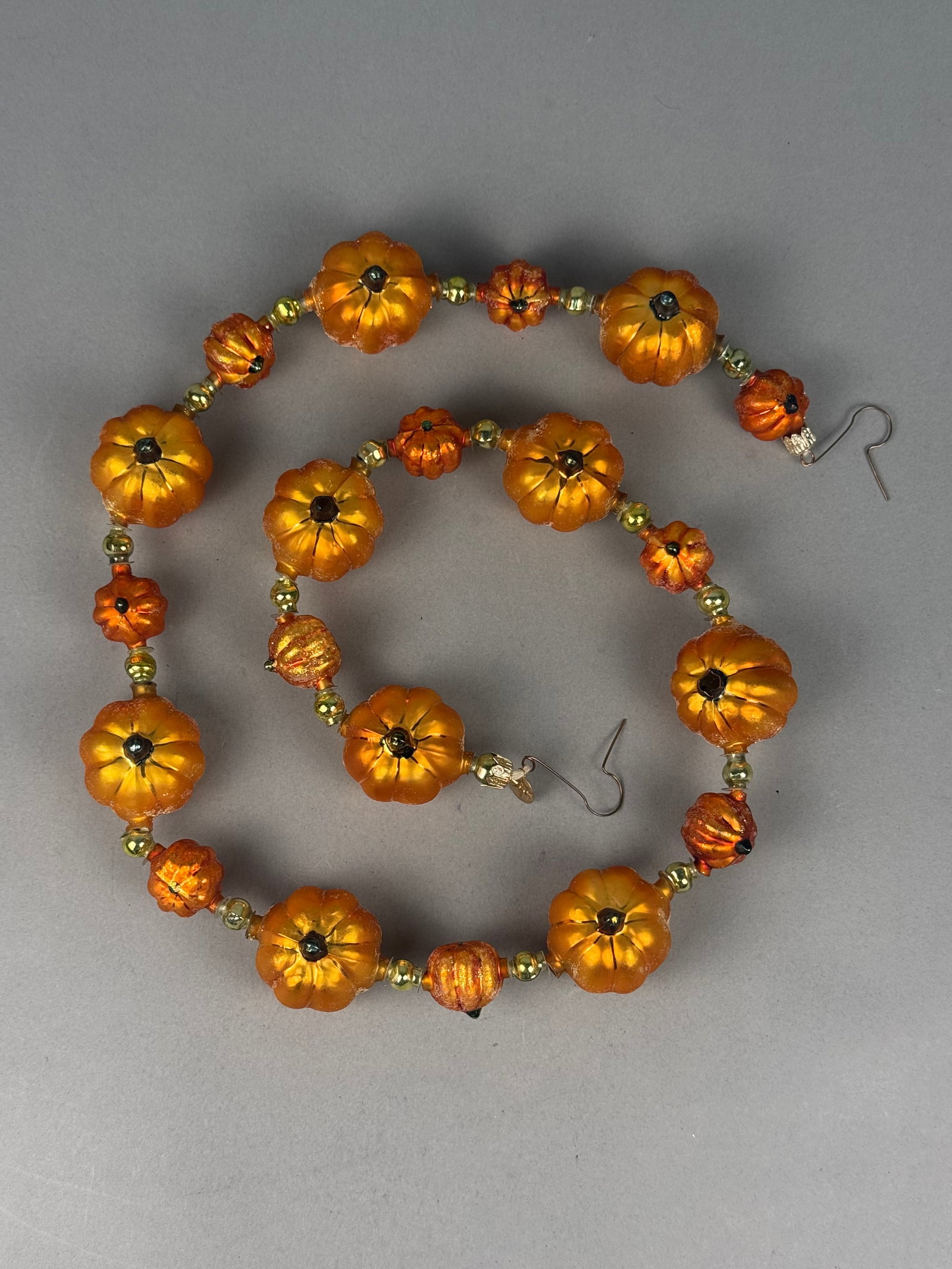 Radko Gourd Line-Up Glass Pumpkin Garland: This glass pumpkin garland by Christopher Radko measures approximately 36 inches in length and features orange gourd-shaped beads with gold-tone accents, original manufacturer box, and tag. Approximat