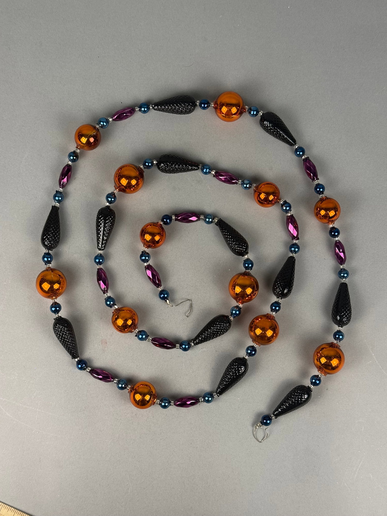 Radko Blown Glass Halloween Bead Garland with Original Box: A hand-blown glass bead garland produced by Christopher Radko, featuring a repeating pattern of decorative beads in a Halloween-themed color palette. . The ends of the garland are finished with metal 