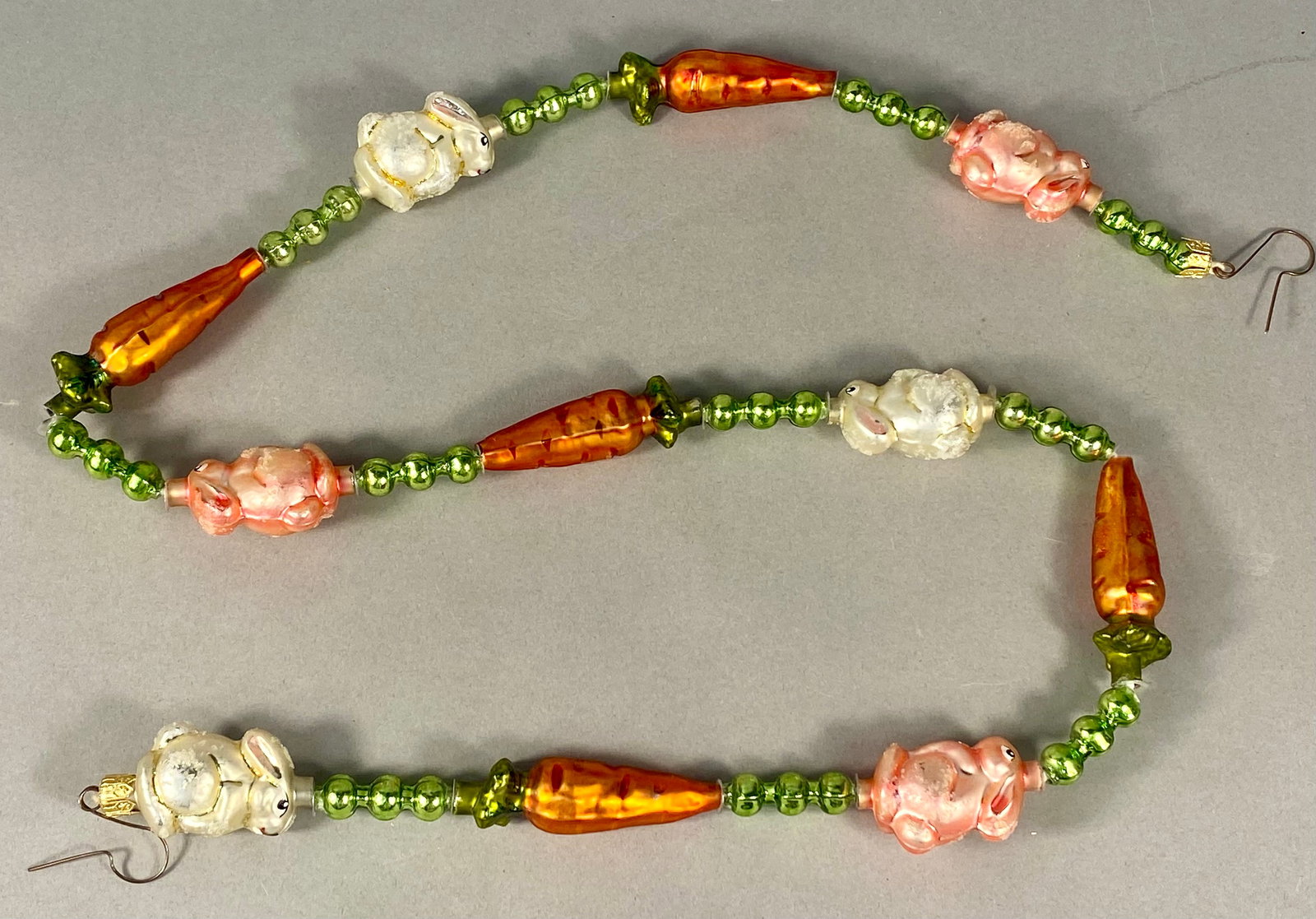 Christopher Radko Bunny Patch Hand Blown Glass Garland: A Christopher Radko hand-blown glass garland in the Bunny Patch pattern. The garland features a recurring sequence of four rabbit beads and four carrot beads separated by clusters of three green spher