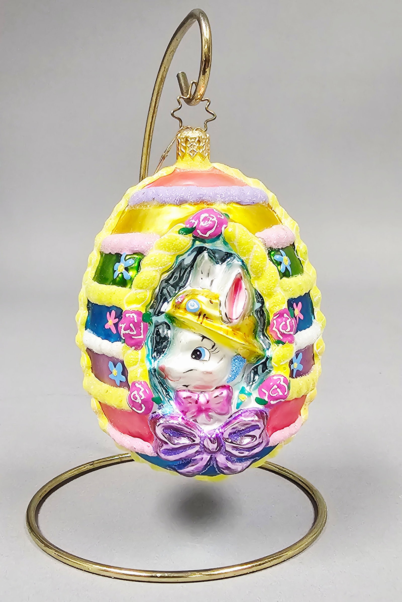 Radko Sugarbunny Sweets Glass Easter Egg Ornament: **Stand Not Included** Christopher Radko Sugarbunny Sweets hand-blown glass Easter ornament. This piece is shaped as an egg with a central opening revealing a three-dimensional white rabbit wearing a 