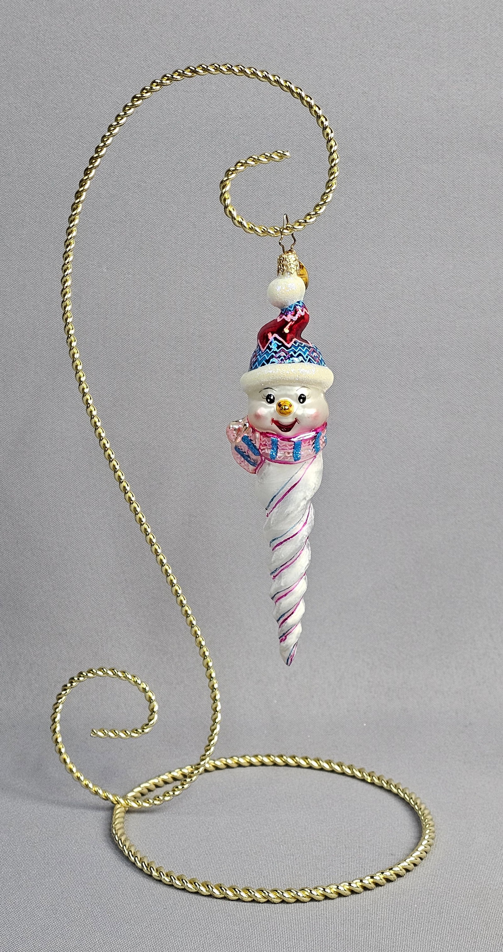 Christopher Radko Hand-Blown Glass Snowman Icicle Ornament: This is a hand-blown glass Christmas ornament produced by Christopher Radko, featuring a snowman icicle design. The piece depicts a cheerful snowman head wearing a red and blue chevron-patterned stock