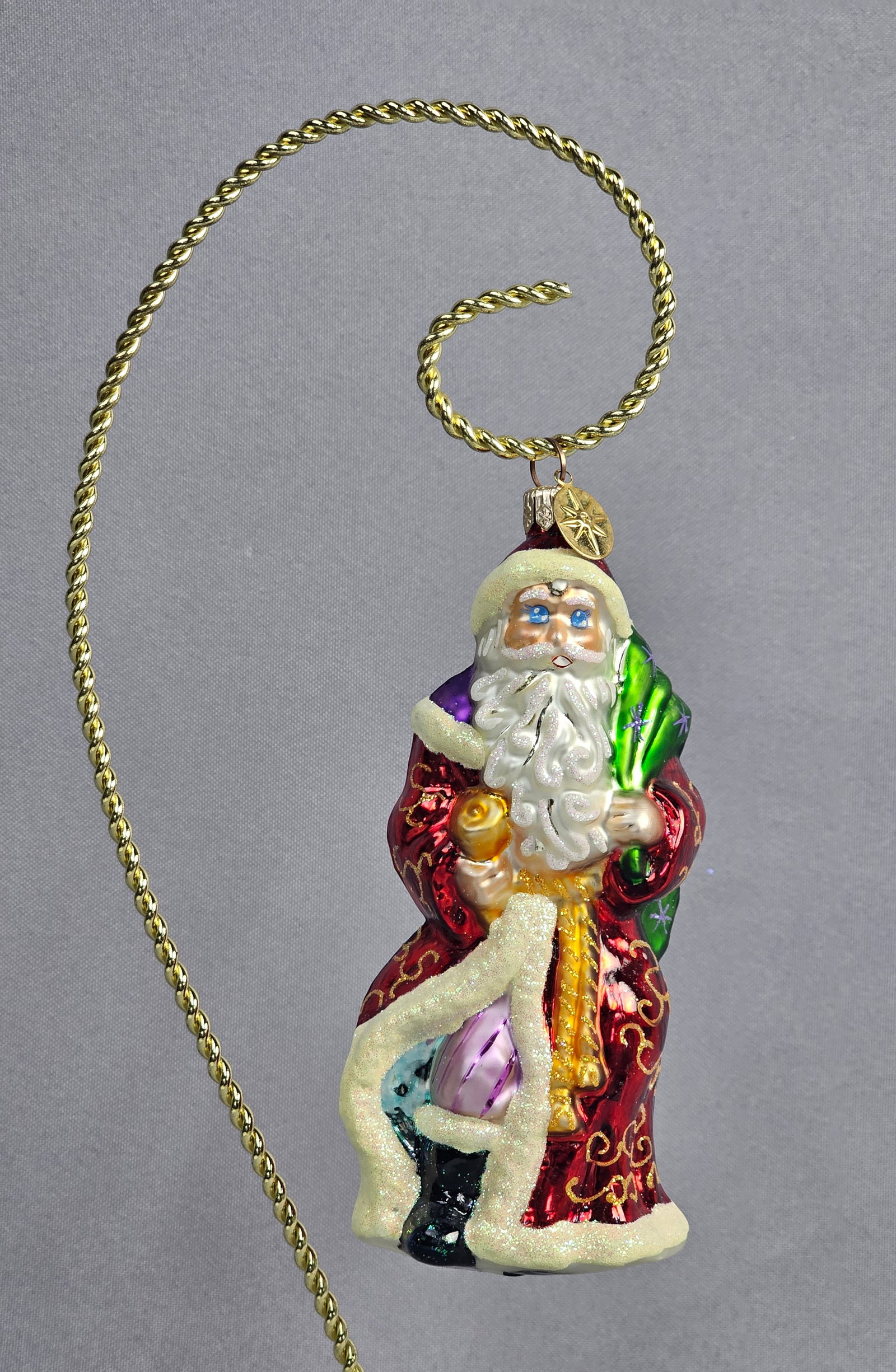 Christopher Radko Hand-Blown Glass Santa Claus Ornament: This mouth-blown glass Christmas ornament is produced by Christopher Radko. The figure depicts a traditional Santa Claus in a metallic red robe embellished with hand-painted gold glitter scrollwork an