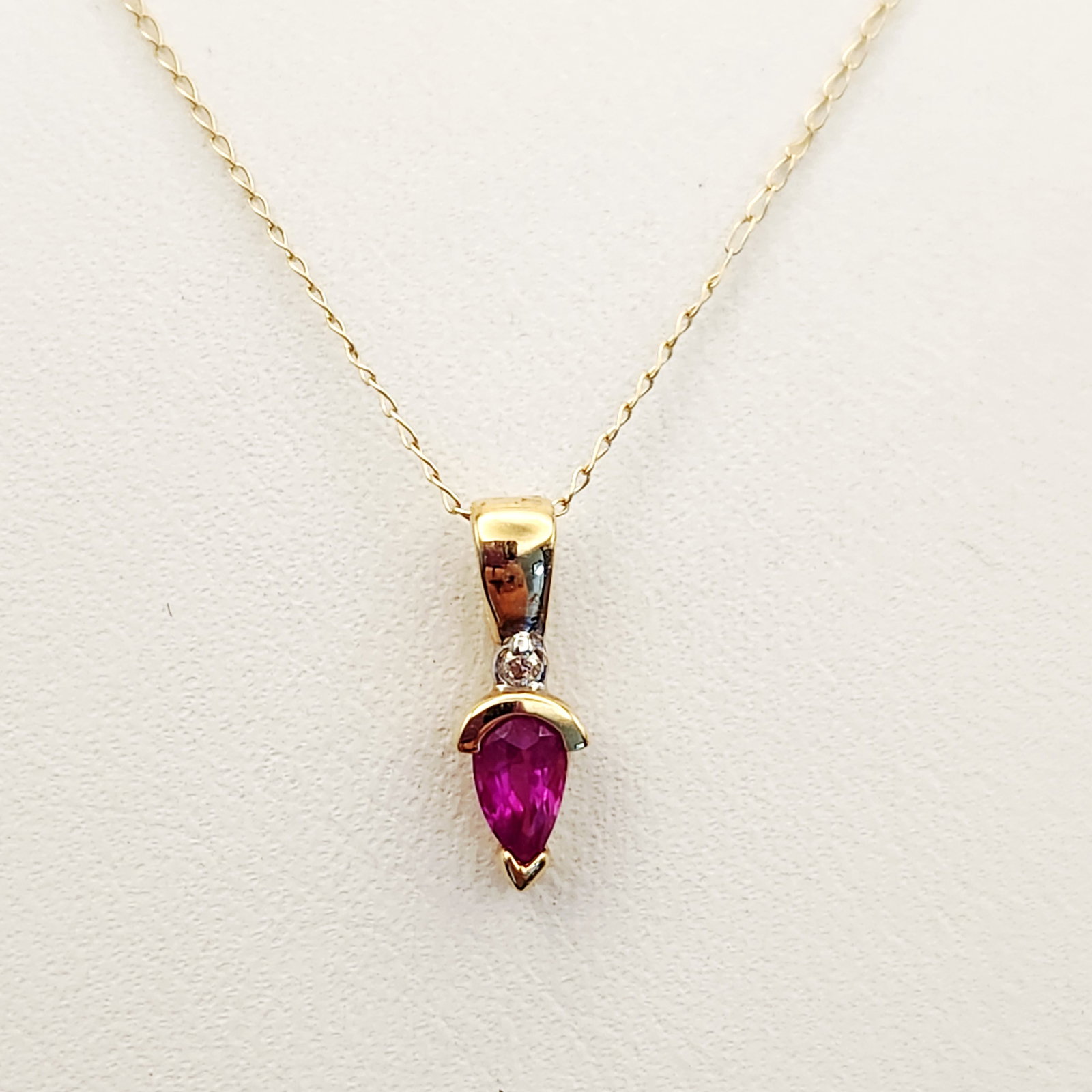 14K Gold Ruby Necklace 0.9 Grams: This necklace features a fine link 14 karat yellow gold chain and ruby pendant. The chain is secured with a spring ring clasp that bears the hallmarks 14K and XL. Chain length: 18 inches Pendant