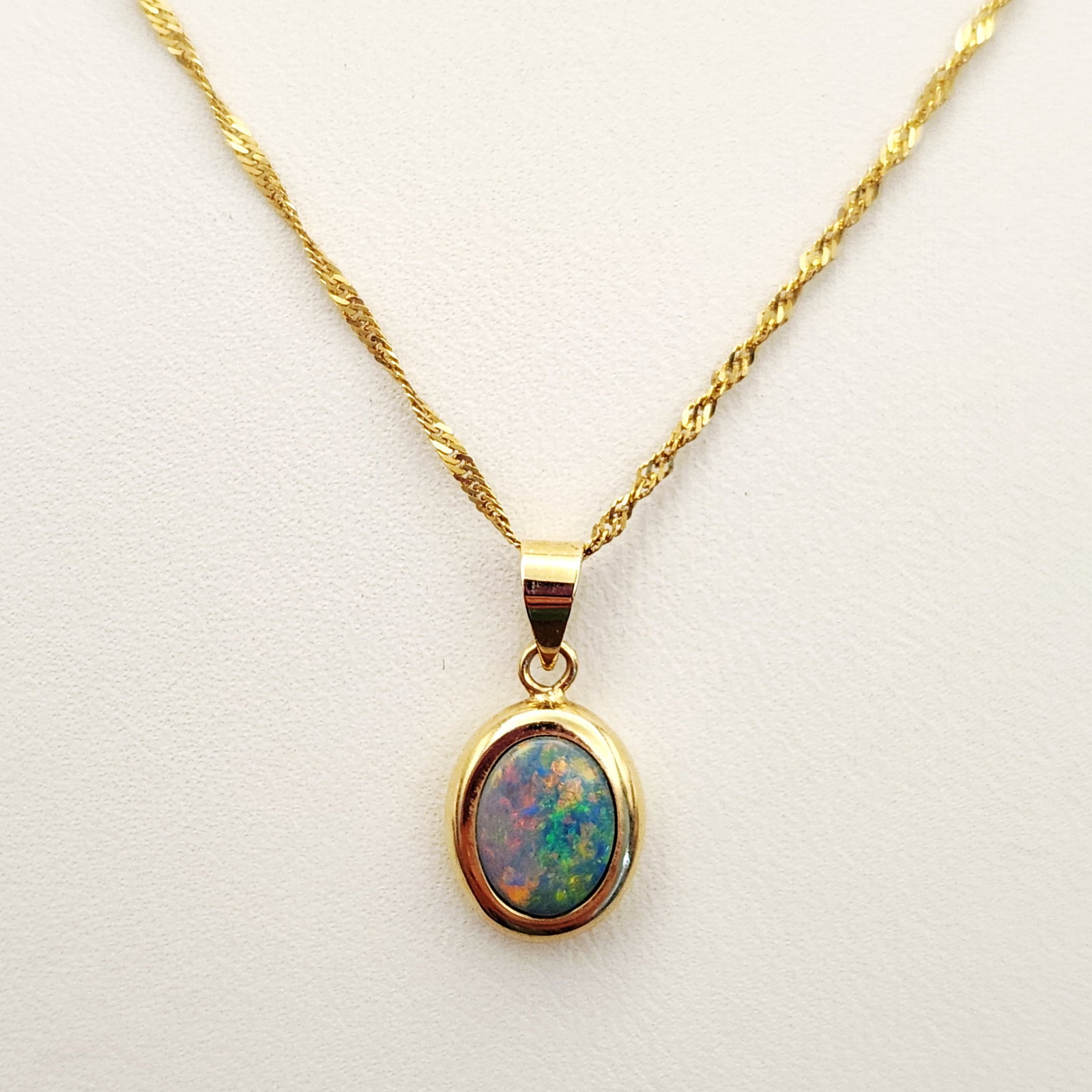 14K Gold Opal Necklace 1.8 Grams: This necklace features an oval cabochon opal pendant bezel-set in 14 karat yellow gold. The reverse of the pendant is stamped with the purity mark 14K585 and a maker's mark consisting of a stylized