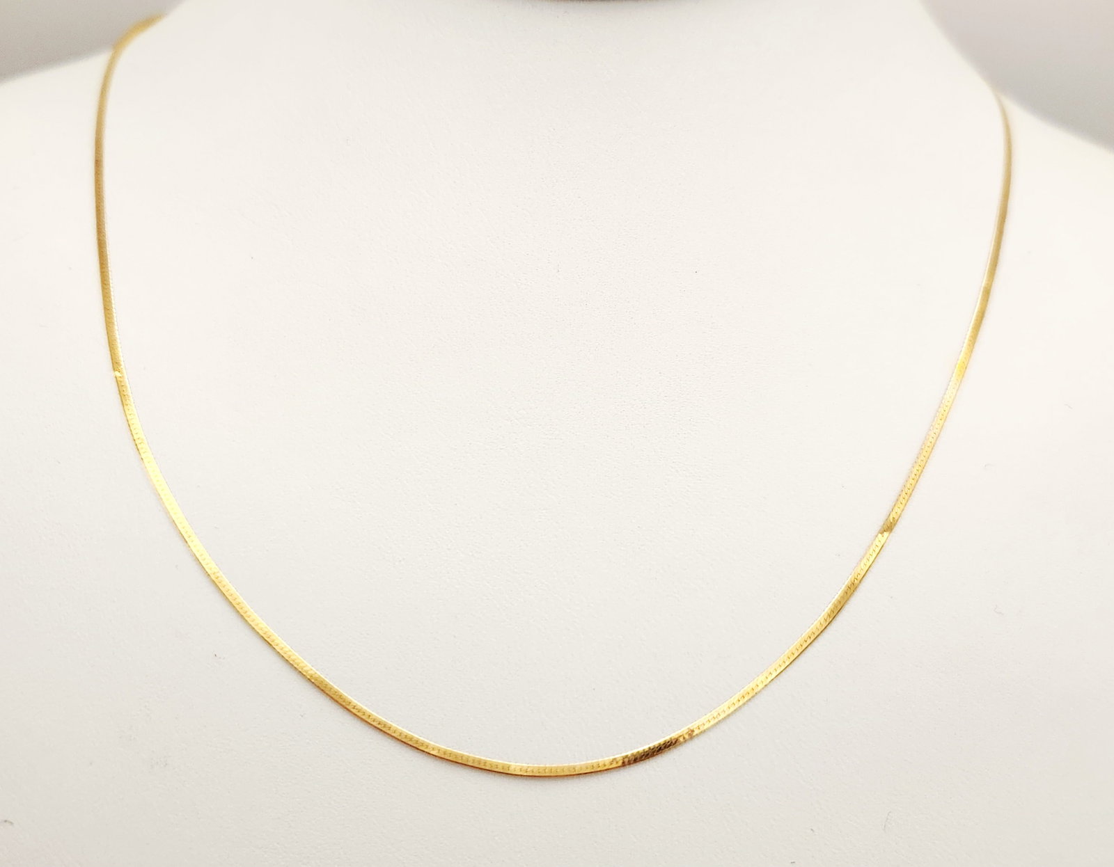 14K Gold Herringbone Necklace 1.3 Grams: A 14kt yellow gold necklace featuring a flat herringbone-style chain with a polished finish. Length: Approximately 18 inches Weight: 1.3 grams. The necklace is in good overall condition. There are