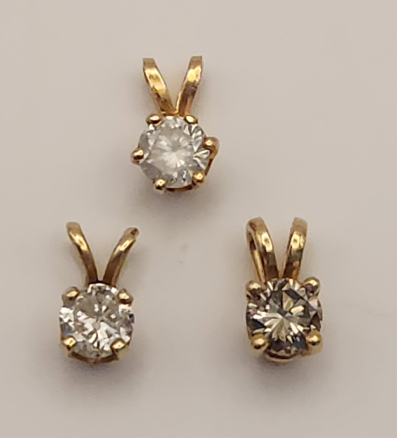 14K Solitaire Pendants 1.4 Grams: This trio of solitaire slider pendants is crafted from 14 karat yellow gold. Each pendant features a single round-cut cubic zirconia measuring approximately 3mm to 4mm in diameter. Total weight: 1.4