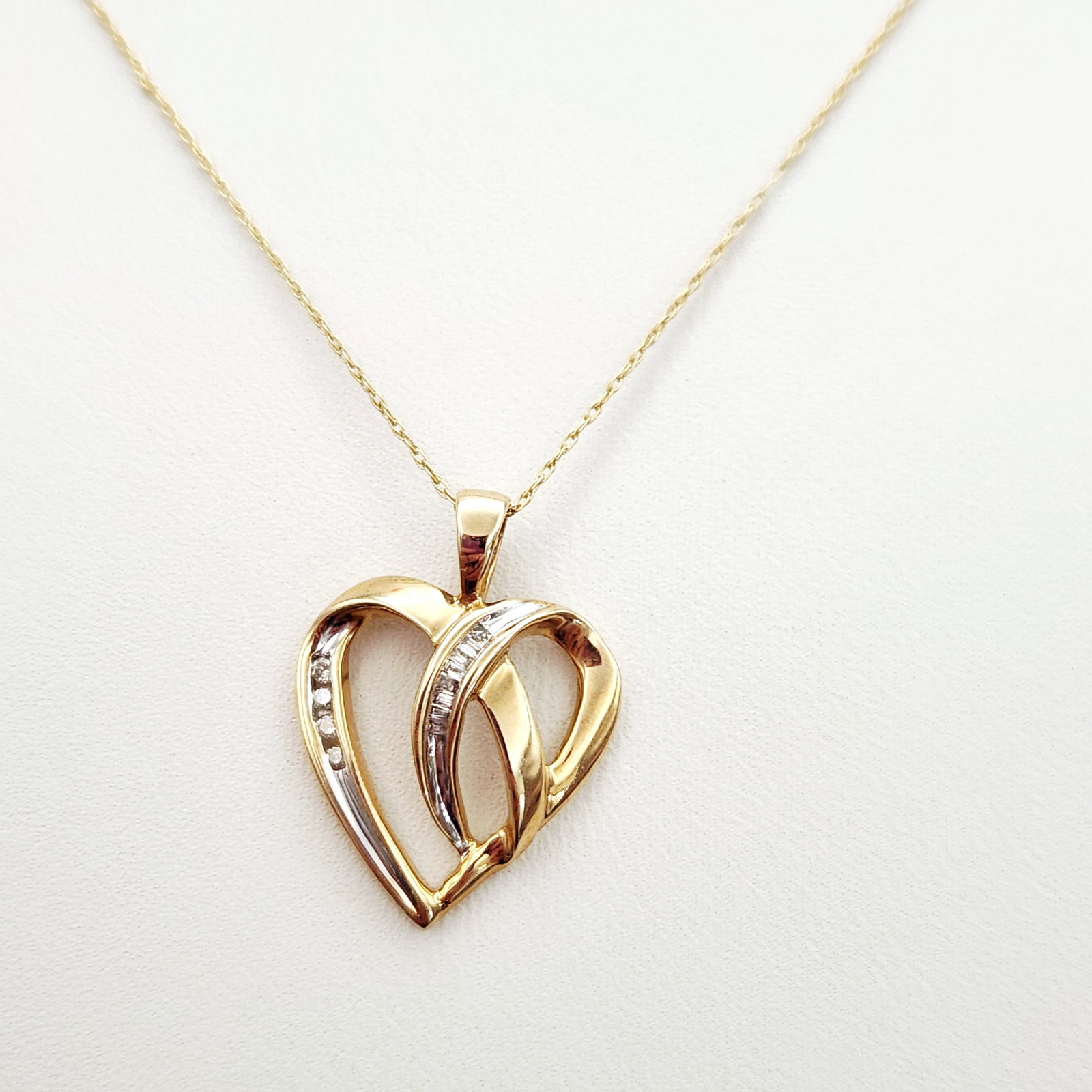 10K Heart Necklace 2.7 Grams: This necklace features a stylized double heart pendant in 10 karat yellow gold. The reverse of the pendant is stamped with 10K and the maker mark GL. The end tag on the chain is stamped with 10KT and