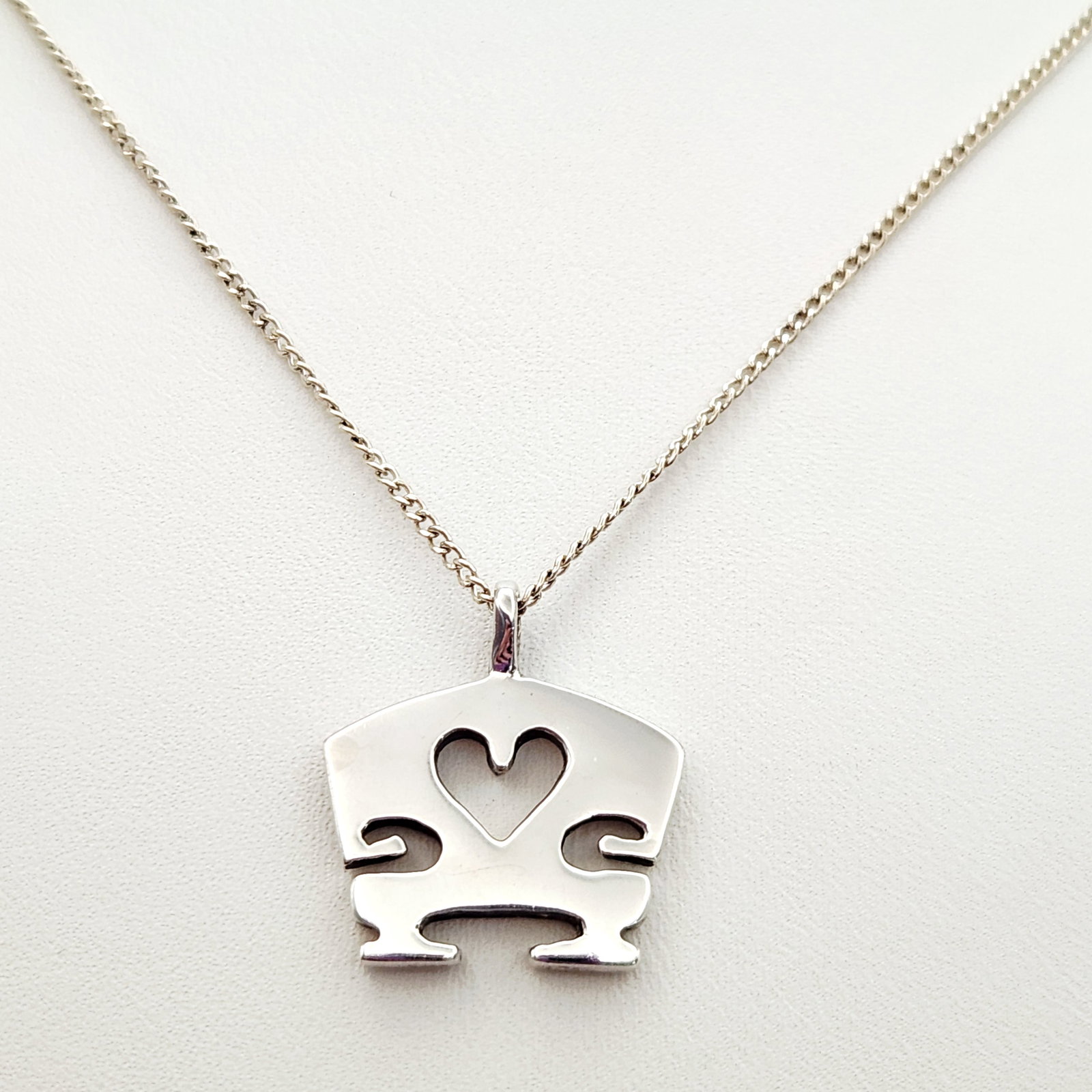 Sterling Stylized Necklace 6.1 Grams: This sterling silver necklace features a stylized pendant. Hallmarks include 925 stamped on the reverse of the pendant and STERLING on the clasp. Pendant width: Approximately 0.75 inches Chain