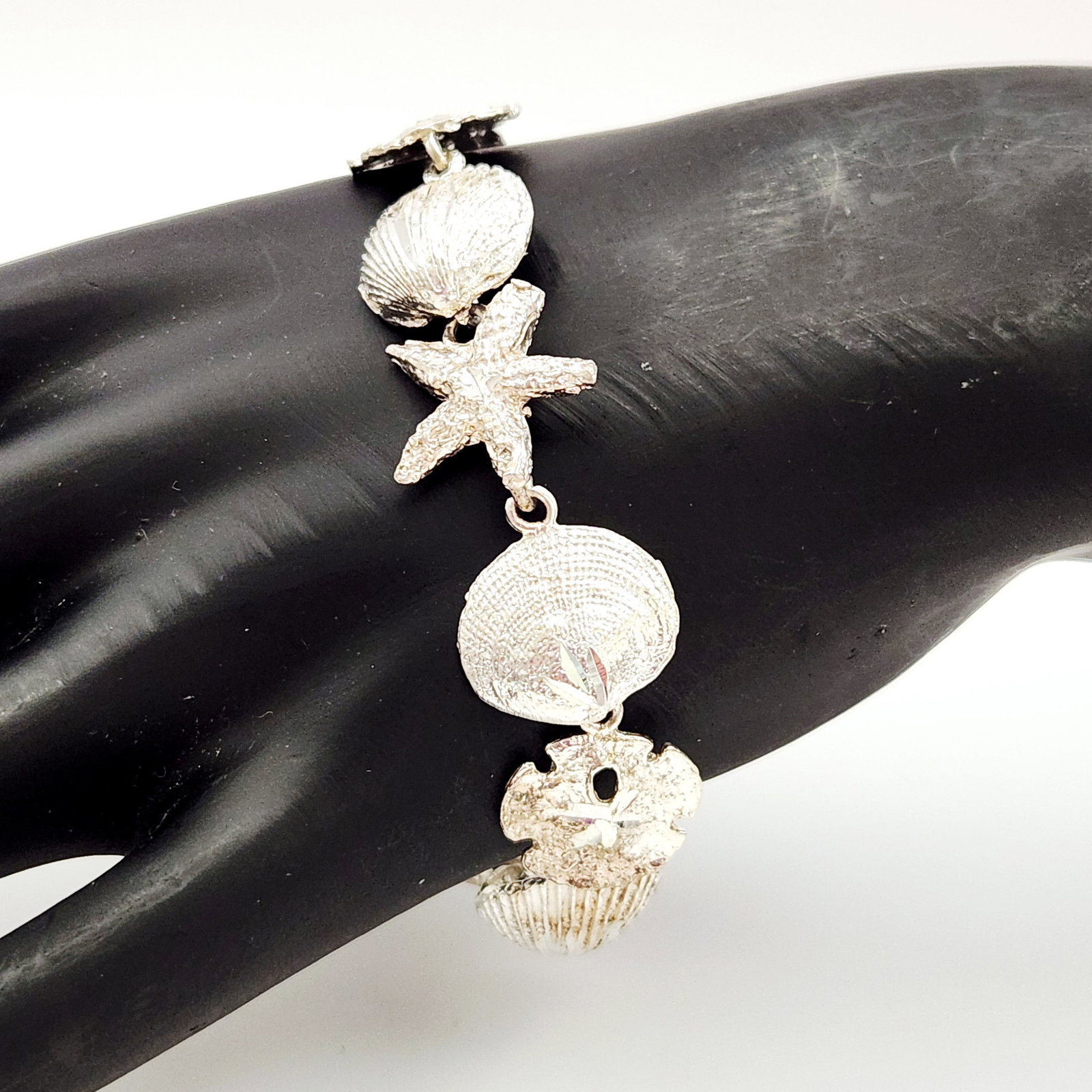 Sterling Marine Bracelet 20.8 Grams: This sea-themed link bracelet is crafted in sterling silver and features an assortment of marine-inspired charms, including scallop shells, starfish & sand dollars. Length: Approximately 7 inches