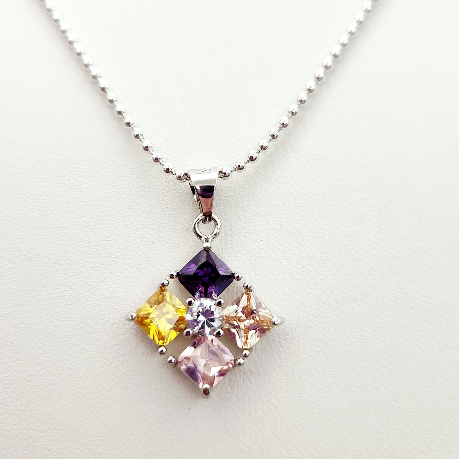 Sterling Gemstone Necklace 5.7 Grams: A contemporary sterling silver necklace featuring a geometric pendant set with five princess-cut multi-colored faceted stones. Weight: 2.5 grams Pendant Width: Approximately 0.5 inches Chain Length: