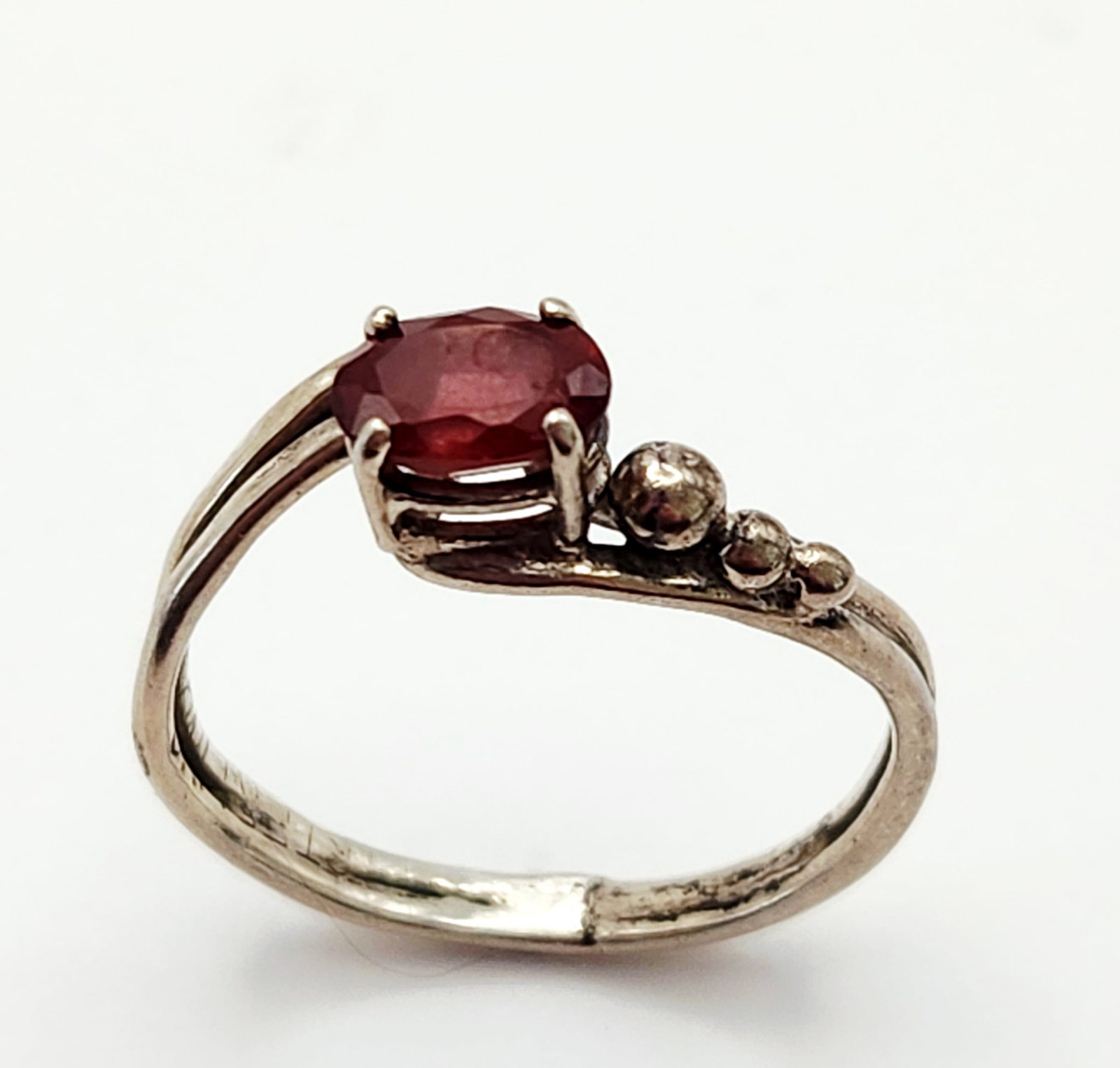 Sterling Ruby Ring 2.3 Grams: A sterling silver bypass ring featuring an oval ruby and three graduated spheres, weighing 2.3 grams and measuring size 7. Overall good condition. Appears to have been resized.