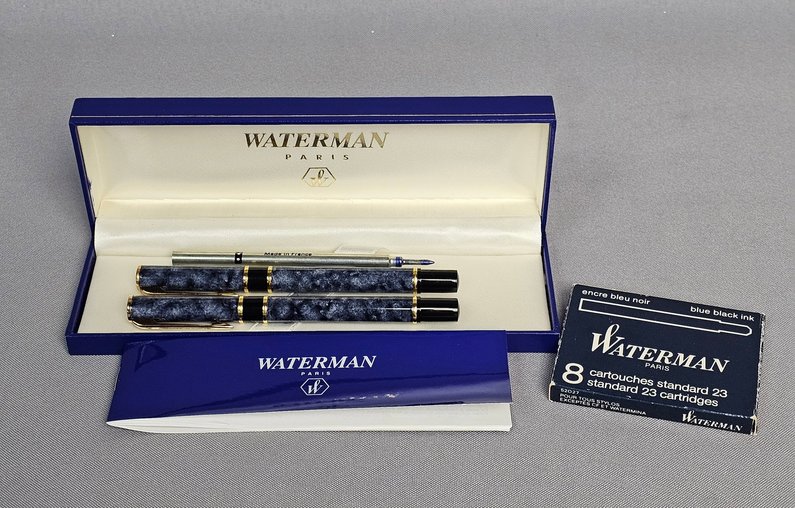 Waterman Marbled Blue and Gold Pen Set: This set of Waterman Laureat writing instruments includes a fountain pen and a matching rollerball pen. Both pens feature a blue and black marbled lacquer finish over metal bodies, accented with