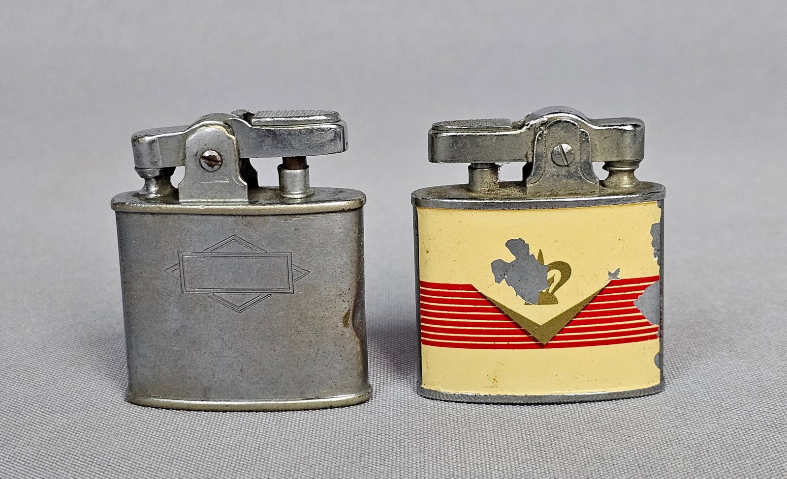 Two Mid-20th-Century Automatic Pocket Lighters: Two vintage automatic pocket lighters of different manufacture and design. The first is a Ronson Standard model with a silver-tone metal case featuring an unengraved rectangular cartouche centered on