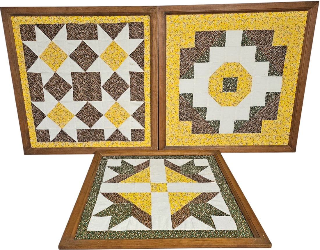 Trio of Framed Hand-Pieced Quilt Blocks: This lot consists of three hand-pieced cotton quilt blocks, each mounted to a panel and displayed within a matching dark wood mitered frame. Each quilt block is wrapped around a panel and secured on