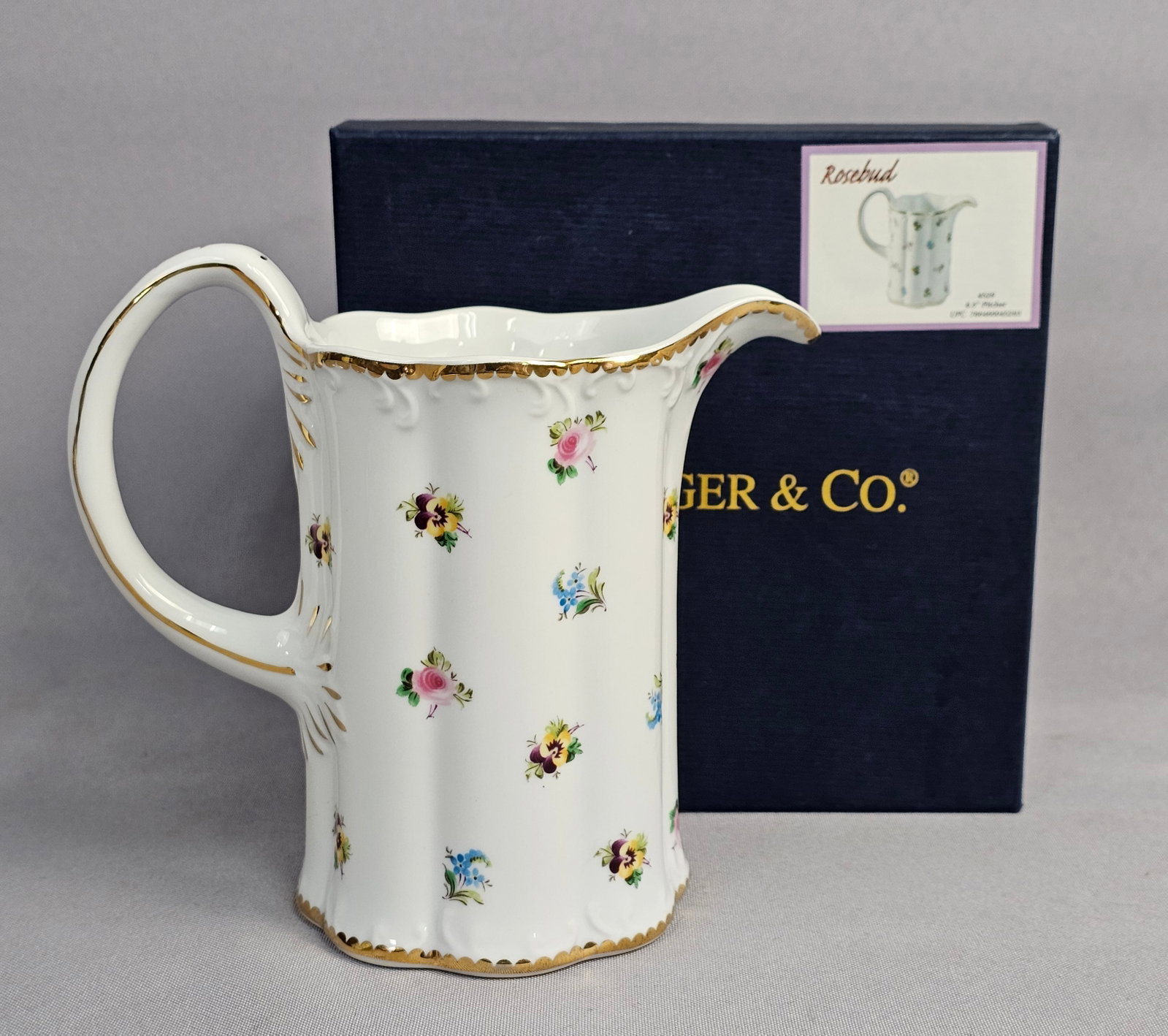 I. Godinger and Co. Rosebud Pattern Fluted Porcelain Pitcher: This fluted porcelain pitcher is produced by I. Godinger and Co. in the Rosebud pattern. The vessel features a tall, cylindrical body with vertical ribs and a scalloped rim. The item is accompanied