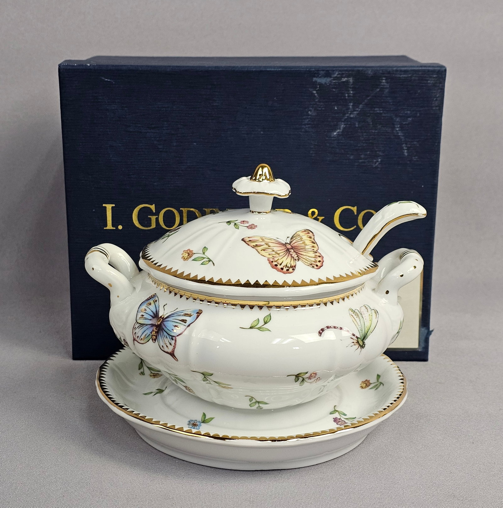 I. Godinger & Co. Primavera Pattern Porcelain Sauce Tureen Set: The set is accompanied by its original blue retail box. Overall Height: 5.5 inches Underplate Diameter: 6 inches The set is in very good condition with no visible chips, cracks, or repairs. There is