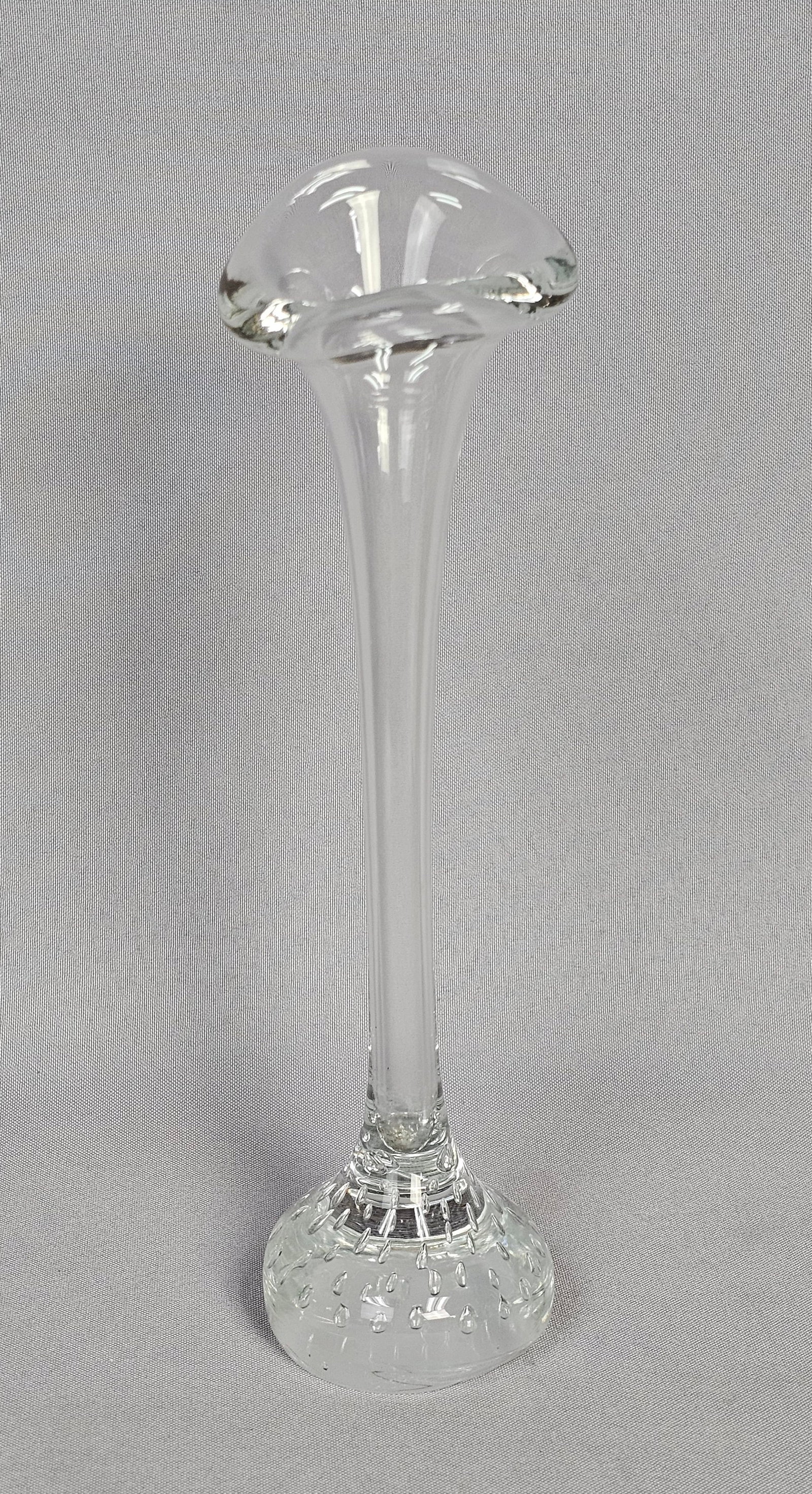 Jack-in-the-Pulpit Vase with Controlled Bubble Base: A hand-blown clear glass vase in the jack-in-the-pulpit form, featuring a tall, slender hollow stem that flares into a wide, undulating rim. The vase is set into a solid, weighted glass base created