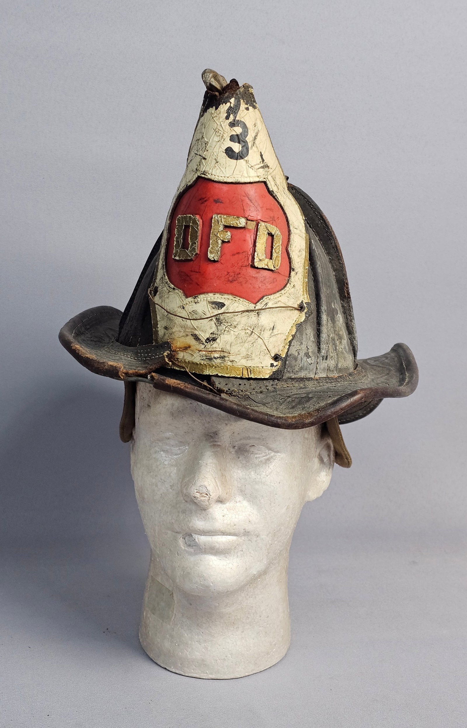 Antique Cairns Leather Fire Helmet with DFD Engine: This antique leather fire helmet is a traditional eight-comb high-crown model manufactured by Cairns. The helmet is constructed of heavy black leather and features a cast metallic eagle finial at the
