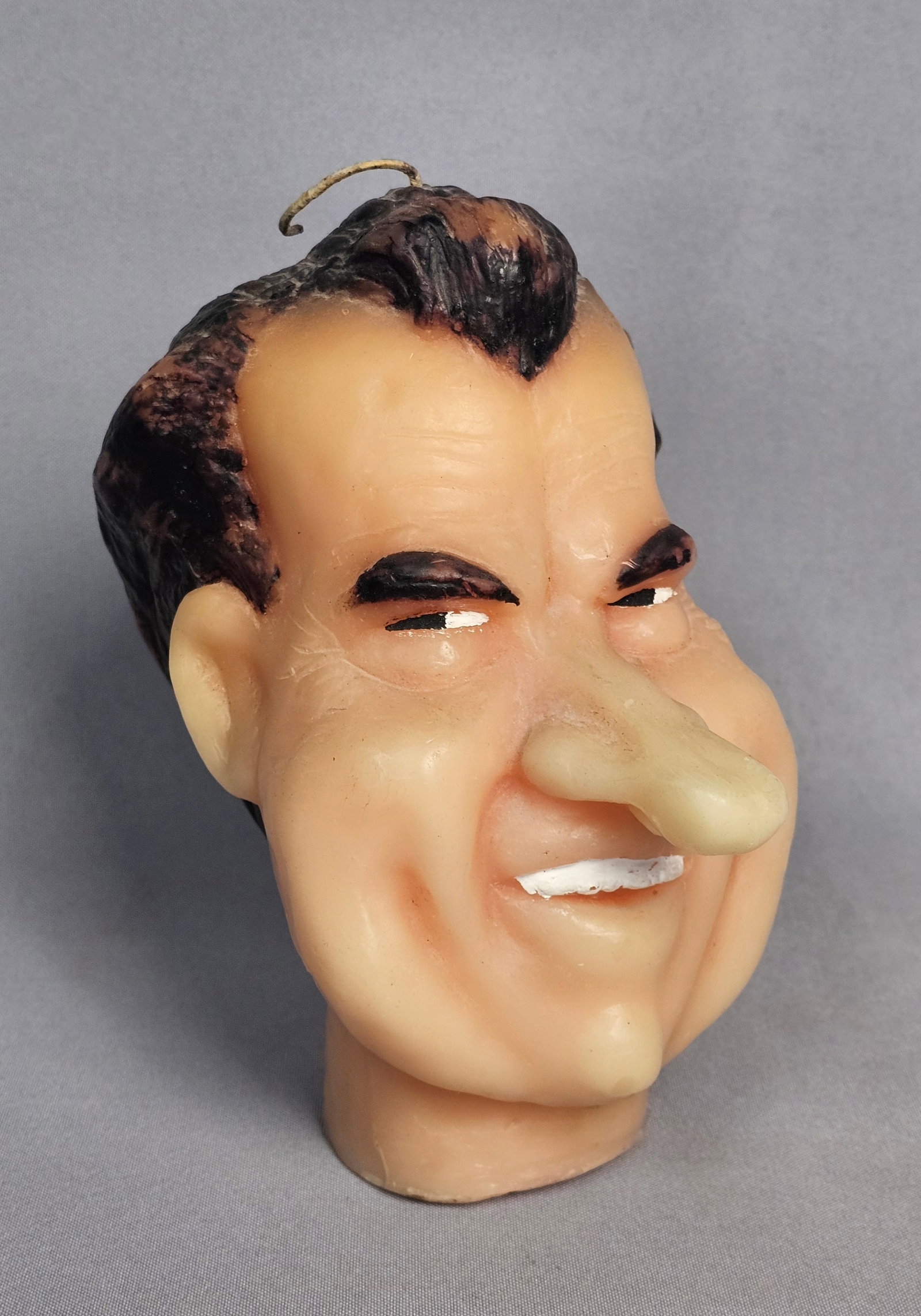 Vintage Richard Nixon Caricature Novelty Wax Candle: This vintage novelty wax candle is a molded caricature depicting former US President Richard Nixon. The figure features exaggerated facial characteristics, including a protruding nose, heavy jowls,