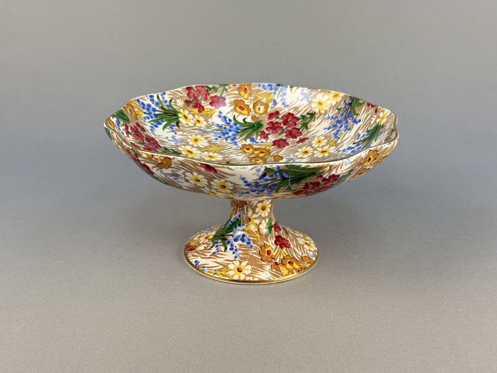 Royal Winton Grimwades Marguerite Chintz Earthenware Bowl: This is a vintage English earthenware pedestal bowl, also referred to as a comport or tazza, produced by Royal Winton Grimwades. The underside of the foot includes a circular backstamp in black ink