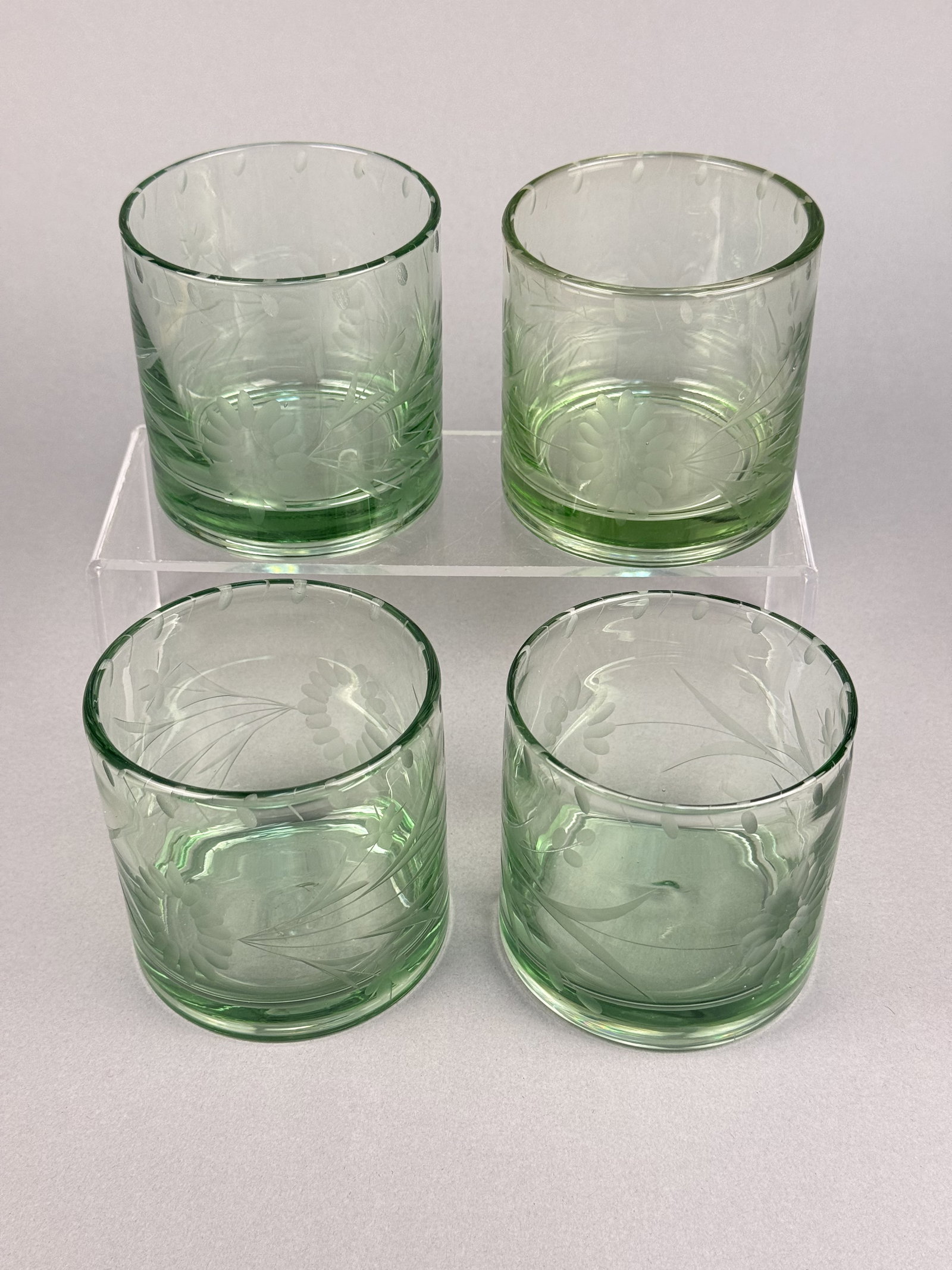 A Set of Etched Green Glass Tumblers: A set of green glass tumblers attributed to Bobby Flay in the BFZ1 pattern. . A continuous border of small, etched oval thumbprints encircles the upper portion of the glass. The glass contains