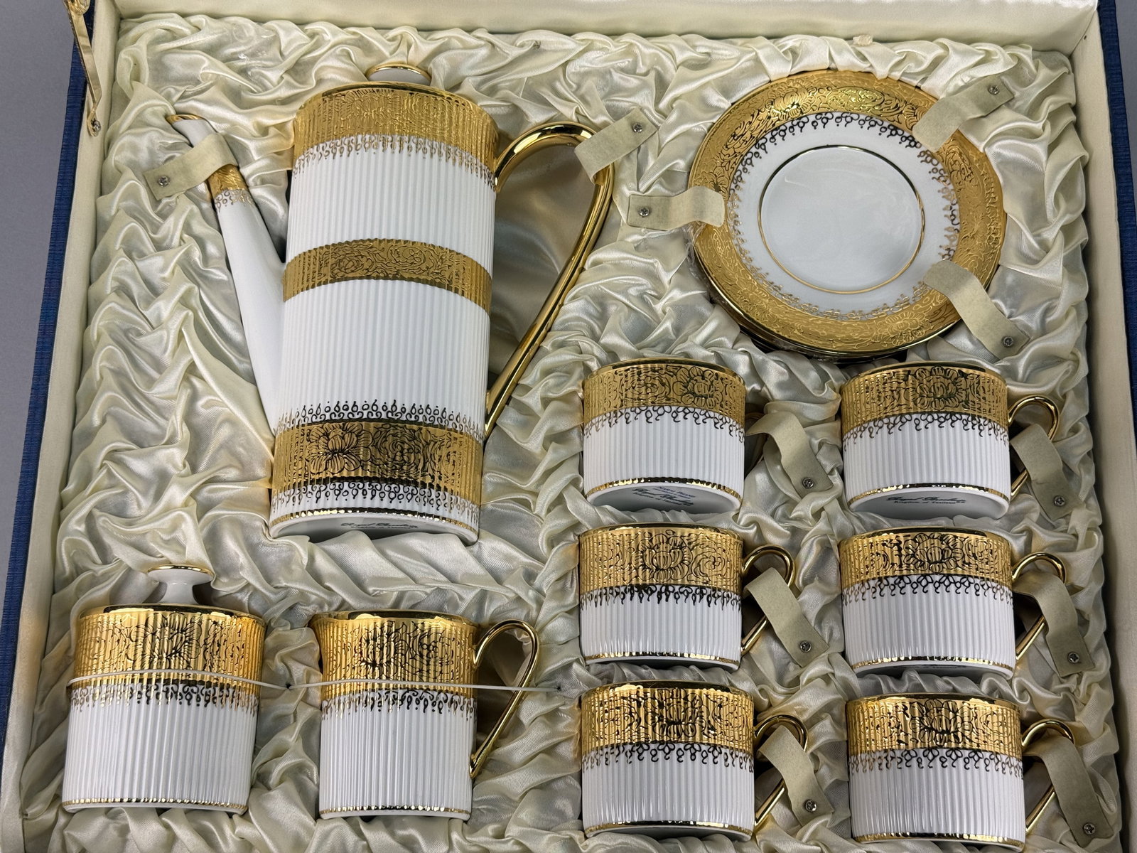 15-Piece Royal Porcelain for Narai Phand Gilt Porcelain Coffee Service: A 15-piece porcelain coffee service manufactured by Royal Porcelain for Narai Phand. The collection includes a tall cylindrical coffee pot with a high-arched gold handle and lid, a lidded sugar bowl,