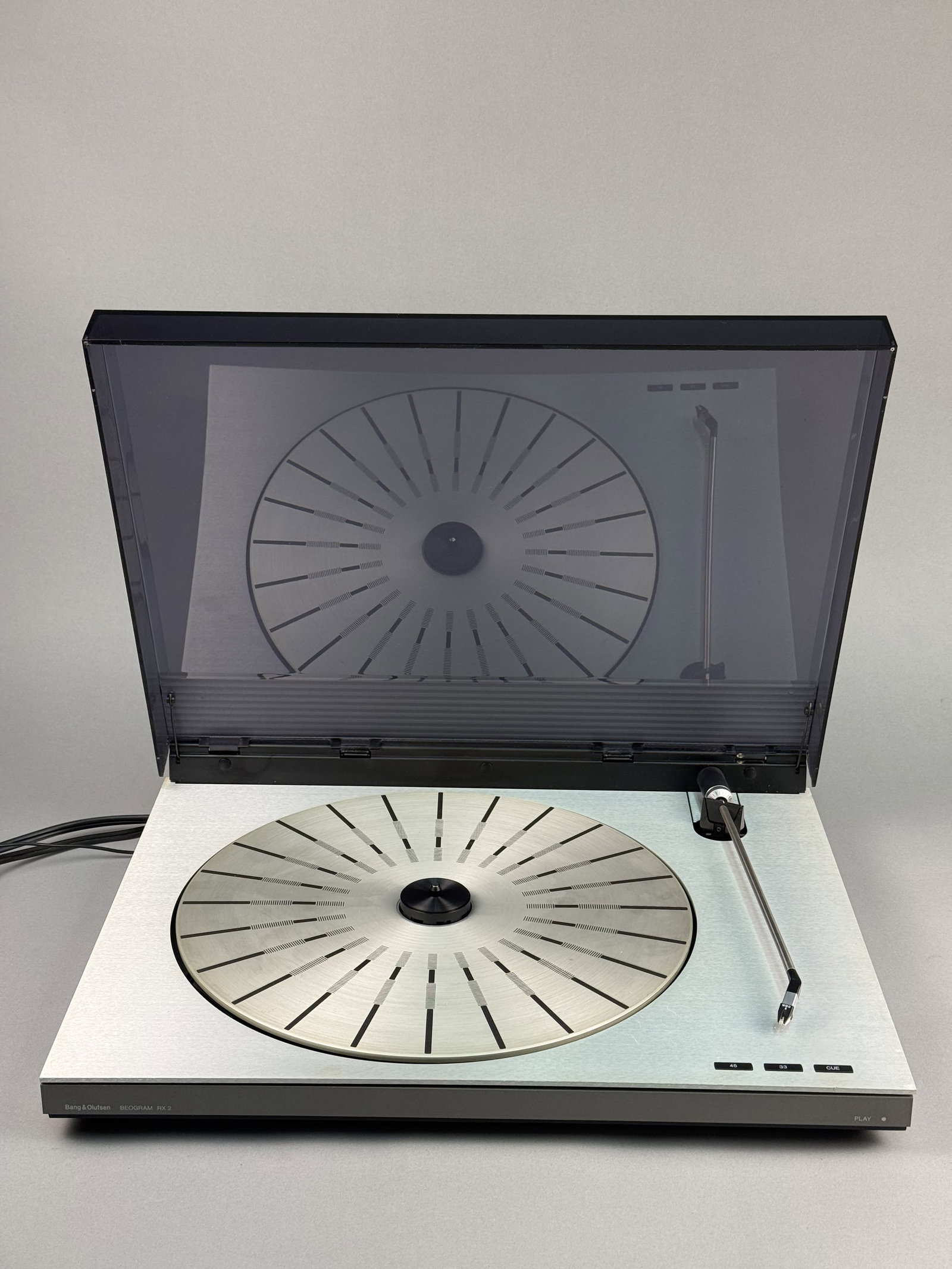 Bang & Olufsen Beogram RX 2 Type 5833 Turntable: A Bang & Olufsen Beogram RX 2 belt-drive turntable, type 5833, designed by Jacob Jensen. The unit is constructed with a brushed aluminum deck, a gray synthetic chassis, and a smoked acrylic dust cover