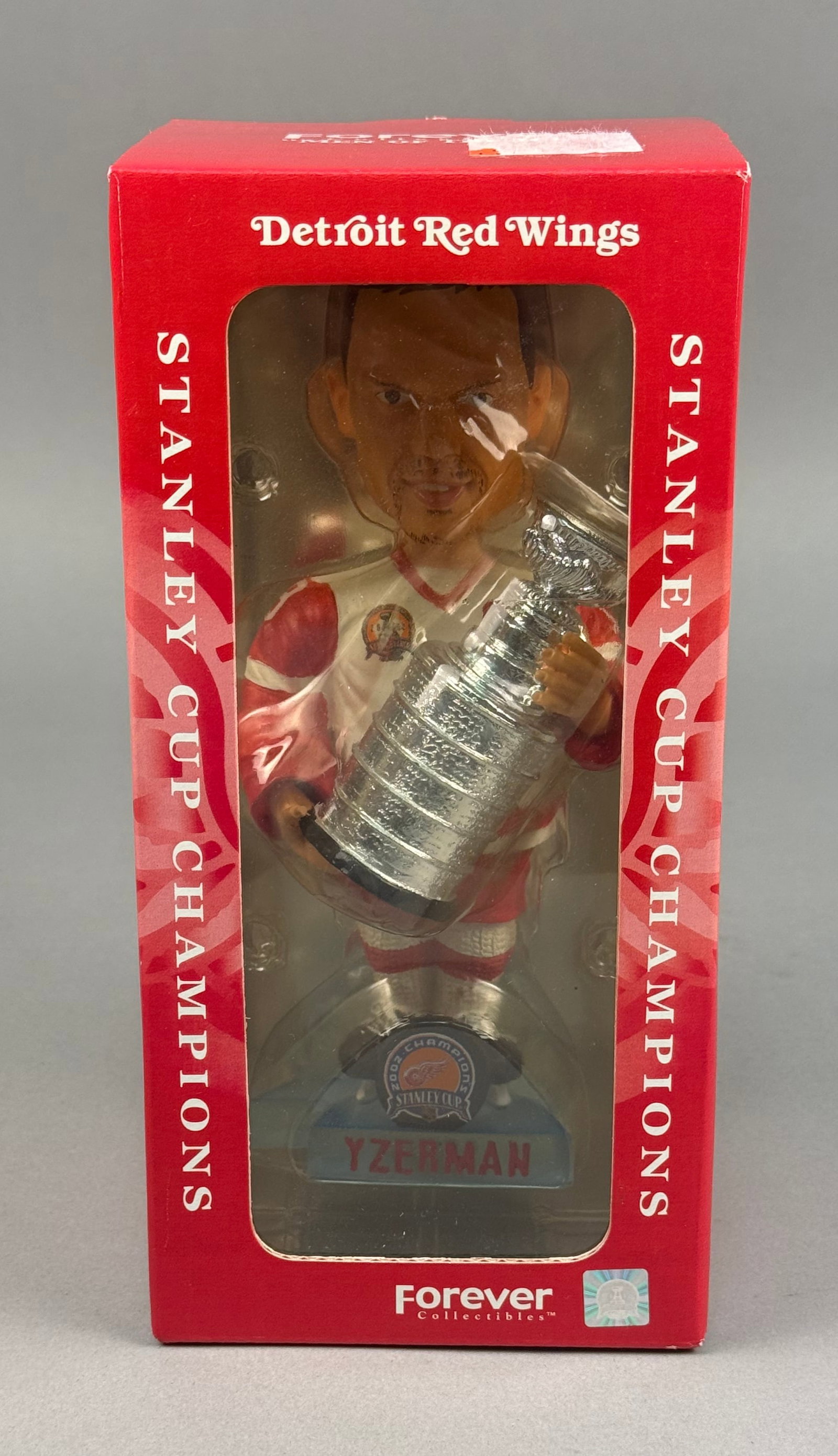 Steve Yzerman Detroit Red Wings 2002 Stanley Cup Bobblehead: This limited edition collectible commemorates the Detroit Red Wings 2002 Stanley Cup championship. The figurine depicts captain Steve Yzerman in a white home jersey with red trim, featuring his name