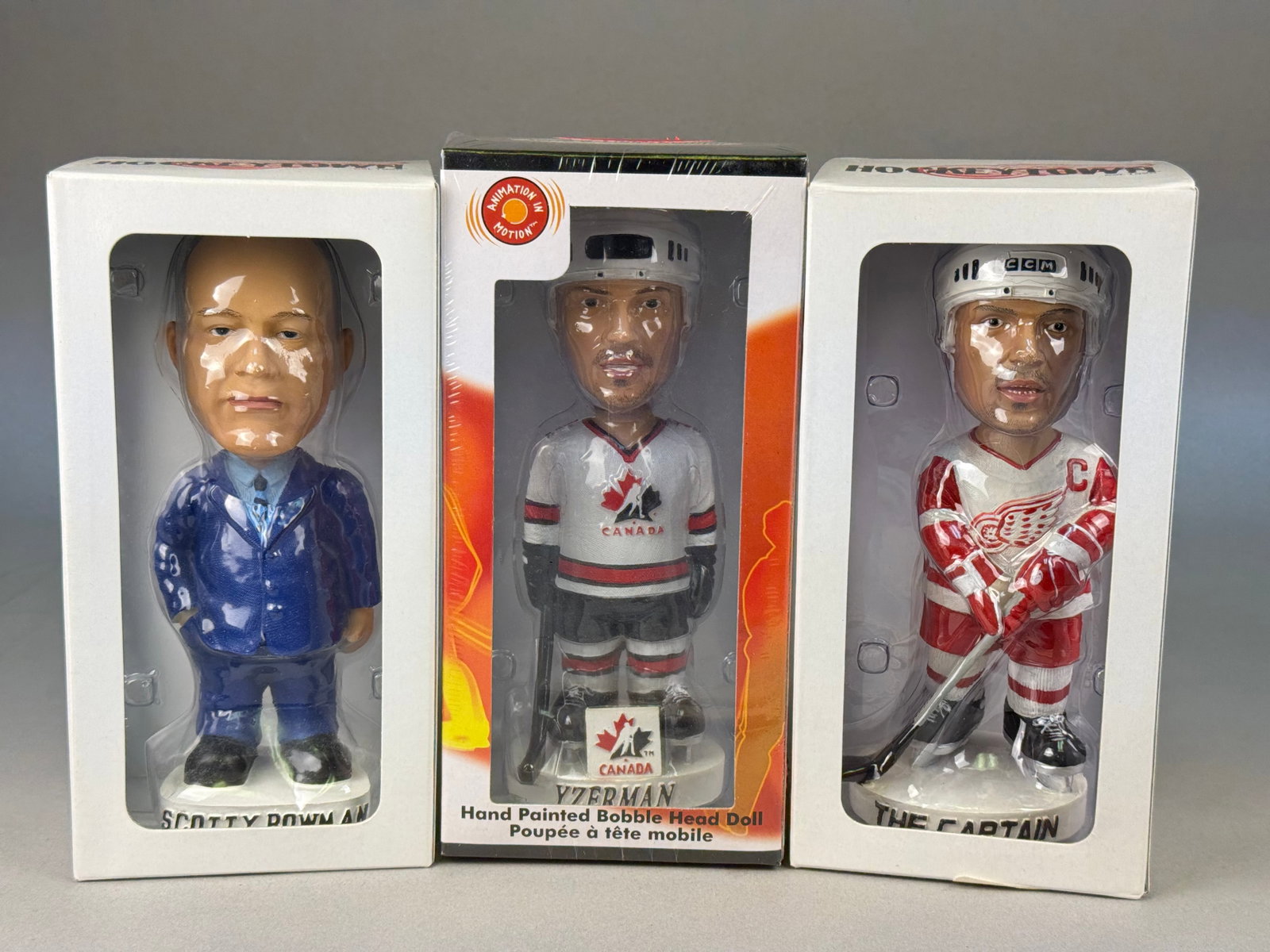Detroit Red Wings & Team Canada Bobblehead Dolls Yzerman & Bowman: A collection of three vintage hand-painted ice hockey bobblehead dolls featuring Detroit Red Wings legends. The first item is a Scotty Bowman bobblehead, depicting the Hall of Fame coach in a blue