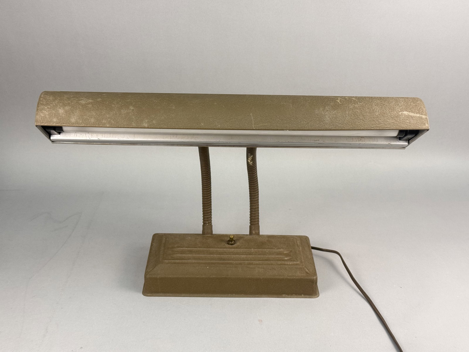 Mid-Century Industrial Double Gooseneck Fluorescent Desk Lamp: The lamp is constructed with a rectangular metal reflector shade housing a single fluorescent tube, supported by two flexible gooseneck arms that allow for adjustable positioning. The rectangular