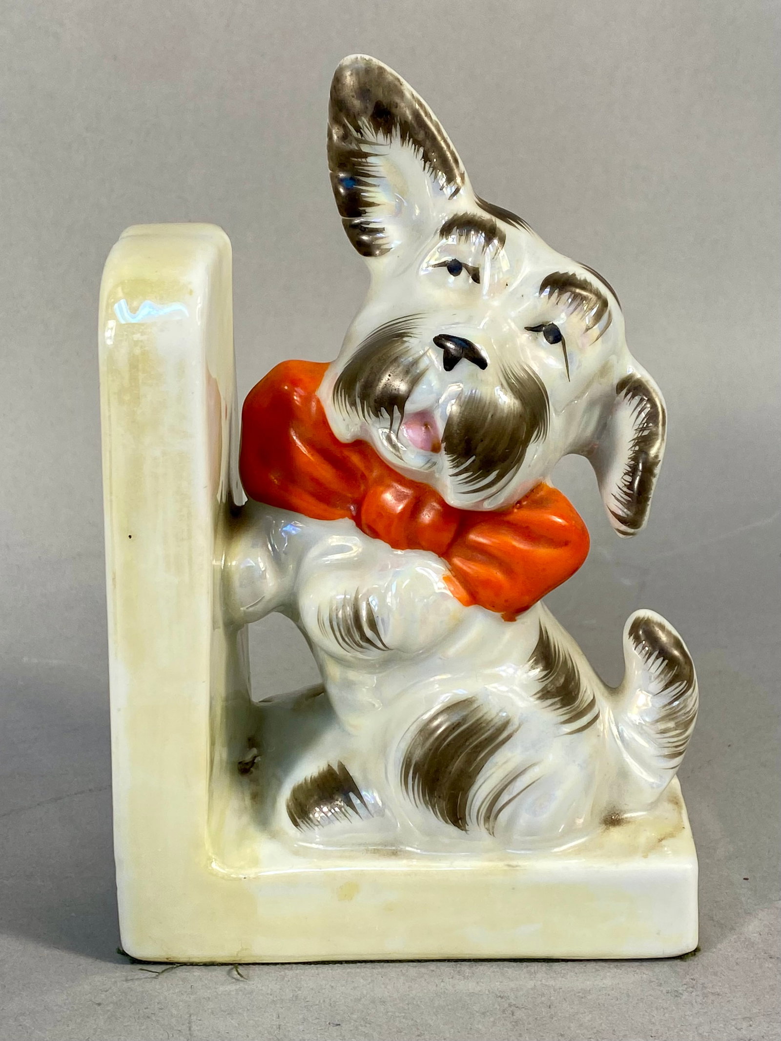 Vintage Japan Lusterware Ceramic Scottish Terrier Bookend: A vintage ceramic bookend featuring a stylized Scottish Terrier dog. The figure is constructed of glazed ceramic with a pearlescent lusterware finish applied to the white sections of the dog coat.