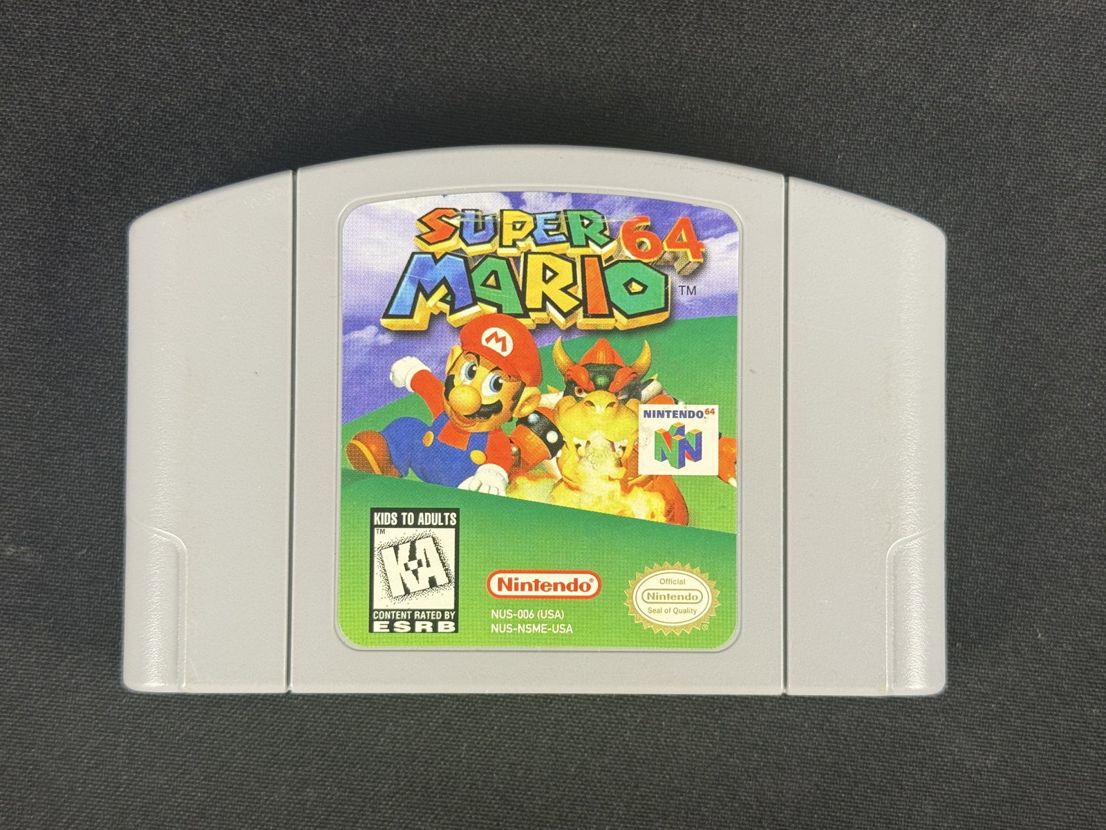 Nintendo 64 Super Mario 64 Game Cartridge, NTSC-U/C: A Nintendo 64 game cartridge for the title Super Mario 64. The unit is manufactured by Nintendo and is the North American NTSC-U/C version. The front label includes the game title, a red Nintendo