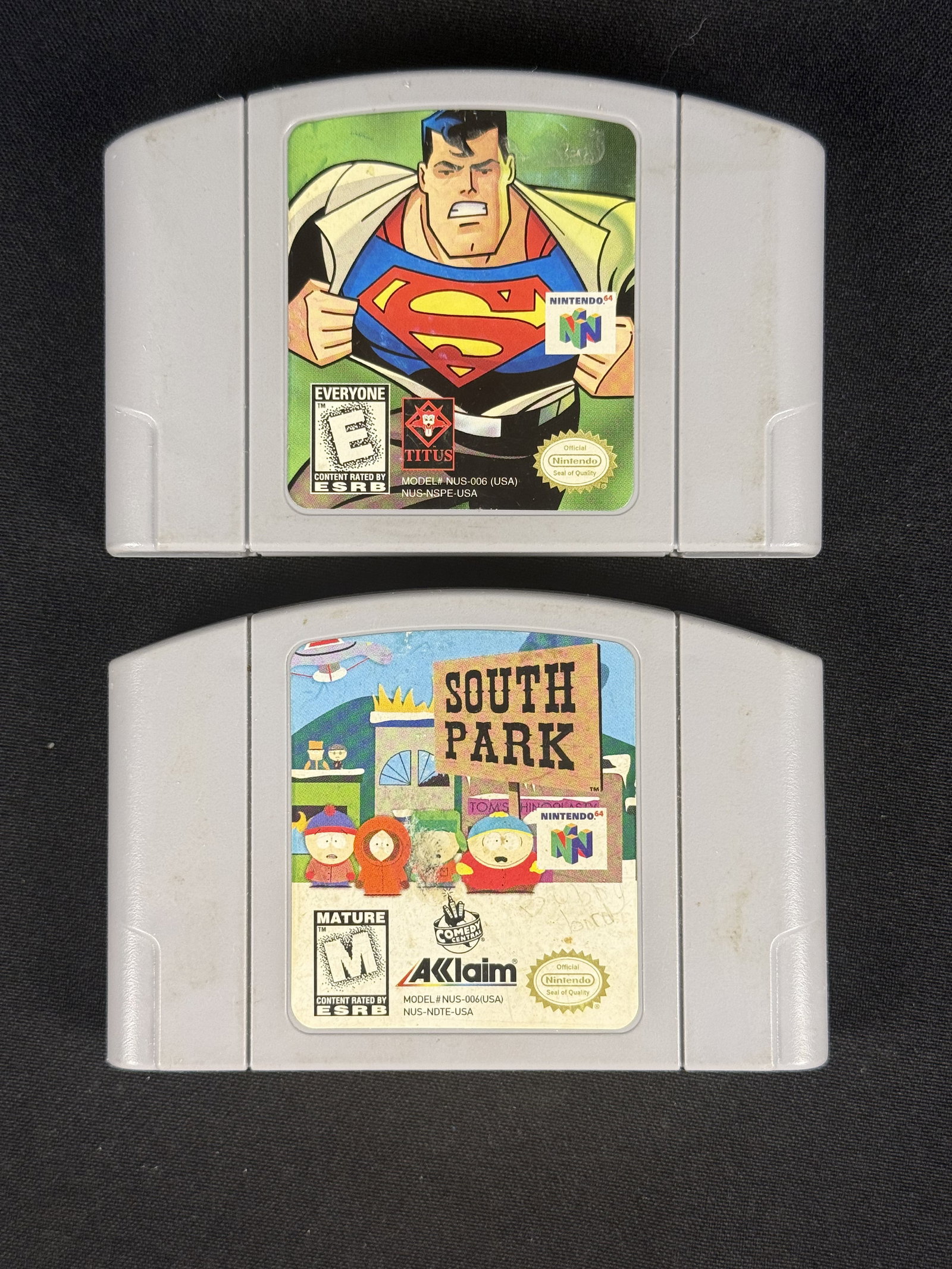 Nintendo 64 Video Game Cartridges, Superman & South Park: This lot features a pair of original Nintendo 64 (N64) video game cartridges for the North American region. The first cartridge is Superman, published by Titus Interactive in 1999. It is housed in a s