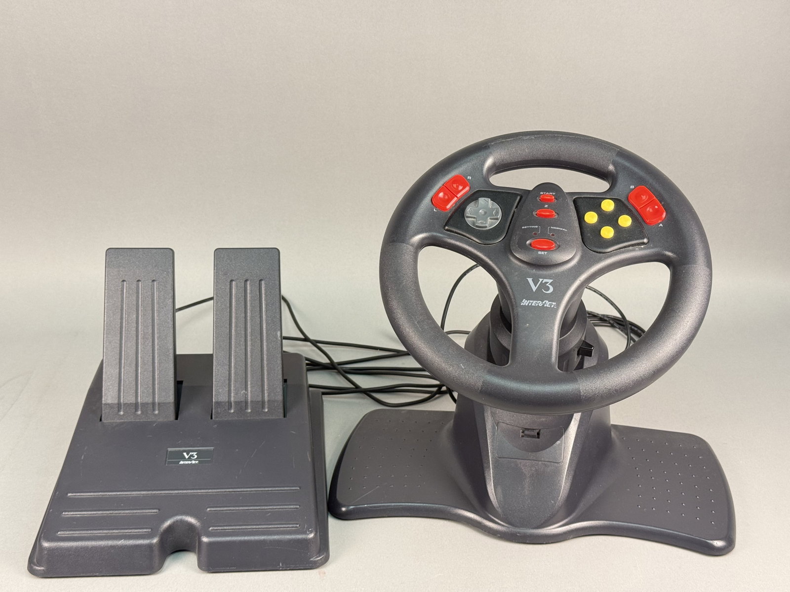 Interact V3 SV-380 Racing Wheel & Pedal Set for Nintendo 64: This Interact V3 model SV-380 racing wheel and pedal peripheral set is designed for use with the Nintendo 64 video game console. The underside of the components contains labels identifying the maker