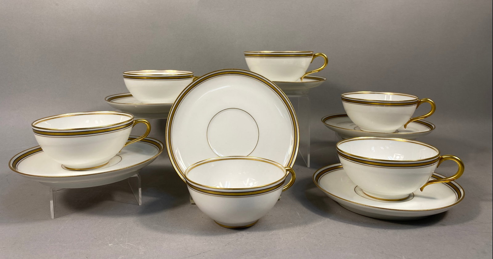 Six Old Abbey Limoges Porcelain Teacups and Matching Saucers: This set of fine white porcelain teacups and matching saucers is manufactured by Old Abbey in Limoges, France. The teacups feature a low, wide-mouthed form with a simple loop handle and a thin gold