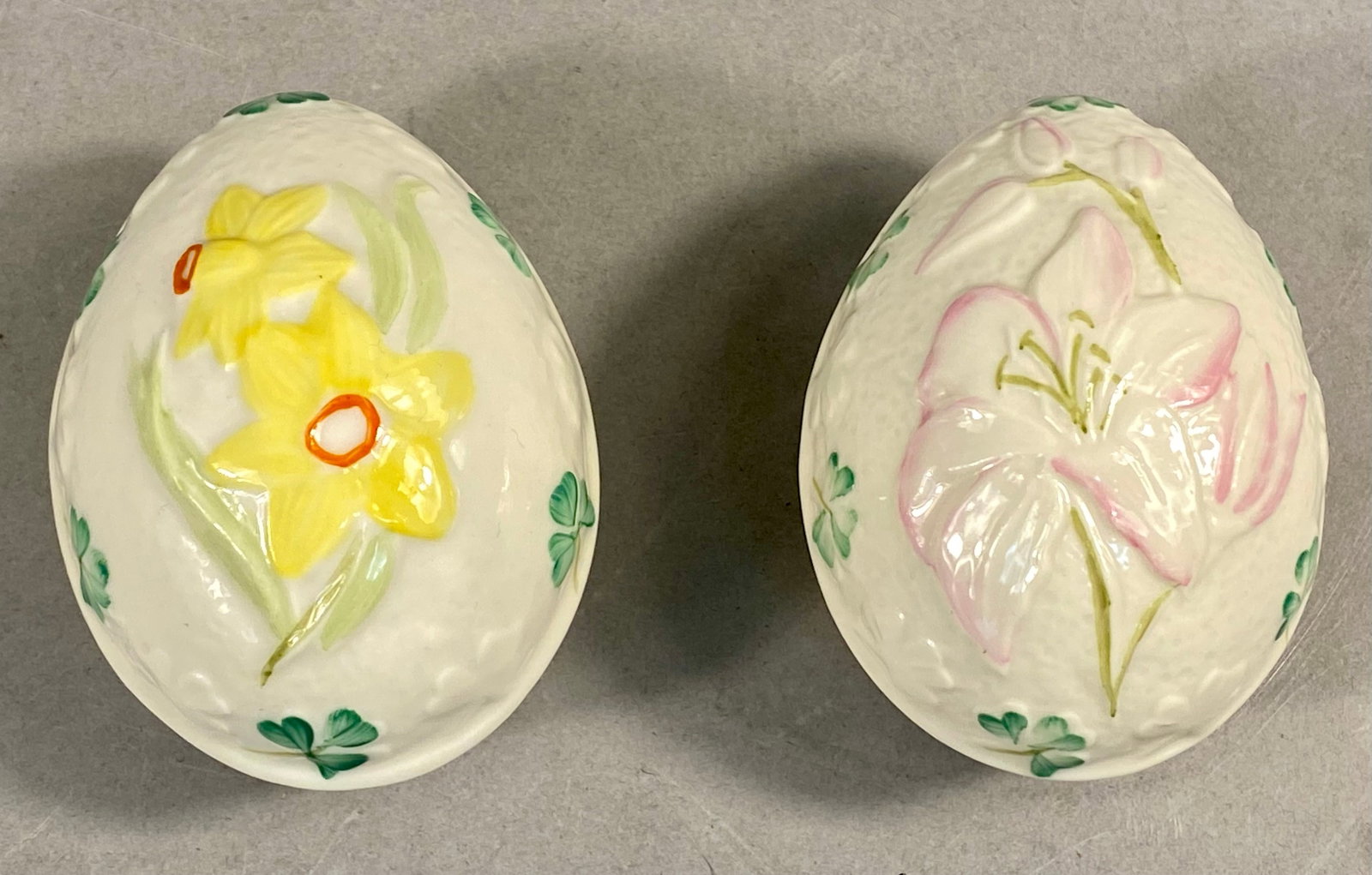 Two Belleek Porcelain Egg Trinket Boxes: This pair of egg-shaped trinket boxes is crafted from fine Parian porcelain by Belleek Pottery of Northern Ireland. Each box features a two-piece construction with a molded basketweave-textured body. 