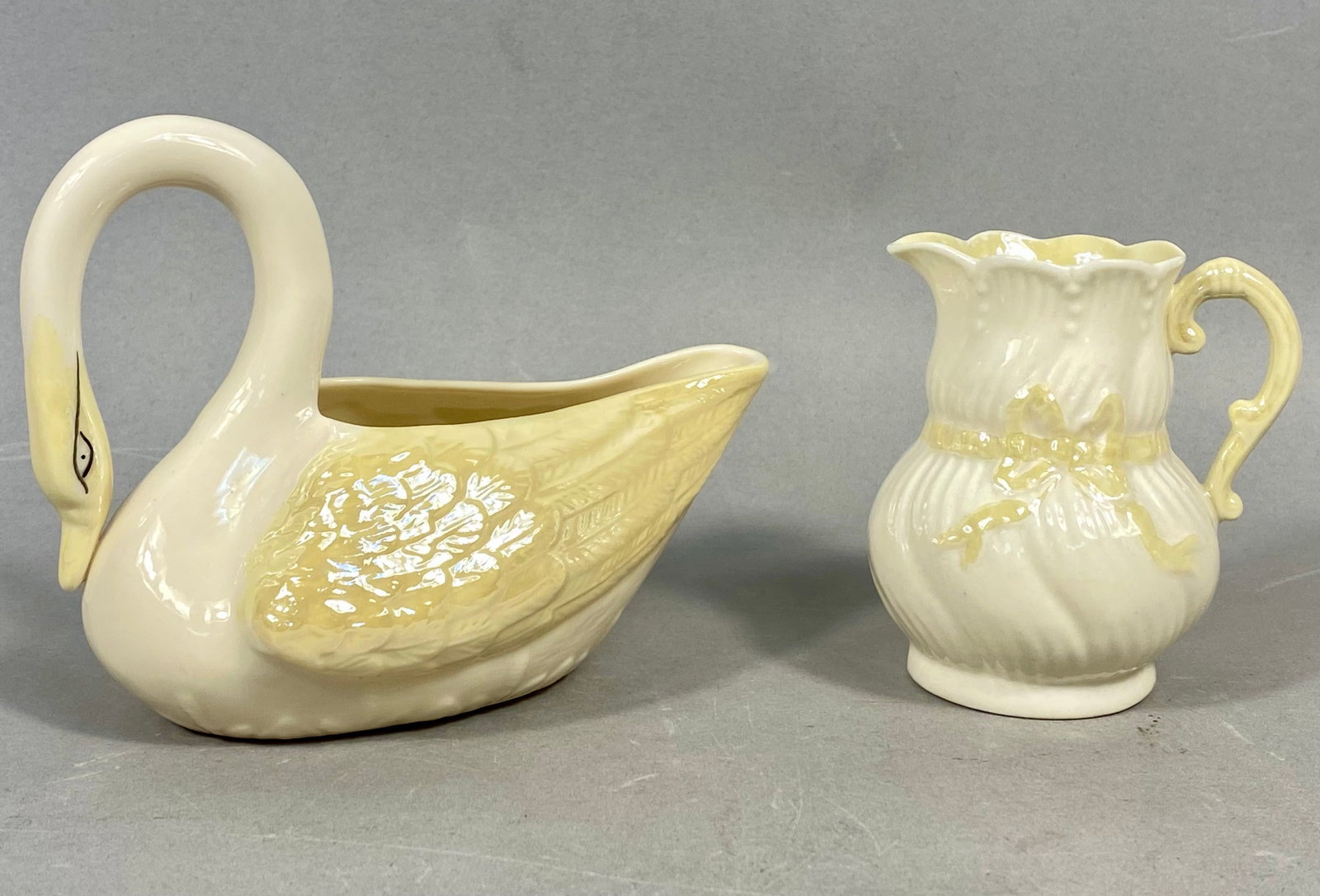 Vintage Belleek Irish Porcelain, Swan Dish & Ribbon Creamer: This lot consists of two pieces of vintage Irish porcelain from Belleek, characterized by the factory's signature Parian body and iridescent pearl-like luster finish. The first item is a swan-shaped o