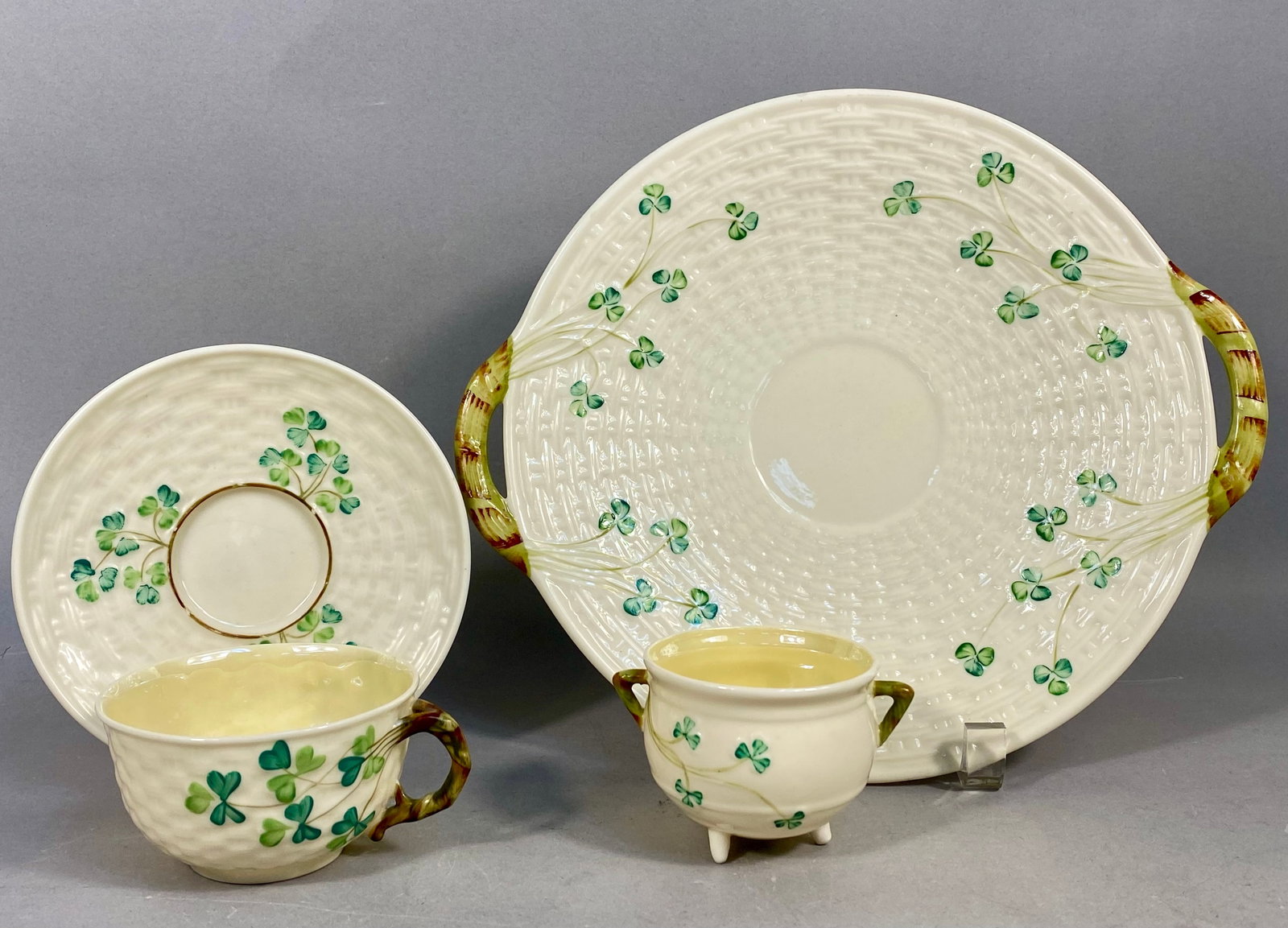 Four Belleek Shamrock Pattern Porcelain Tableware Items: This is a collection of four pieces of Parian porcelain manufactured by Belleek Pottery in Ireland, featuring the traditional Shamrock pattern. The set is characterized by a molded basketweave texture